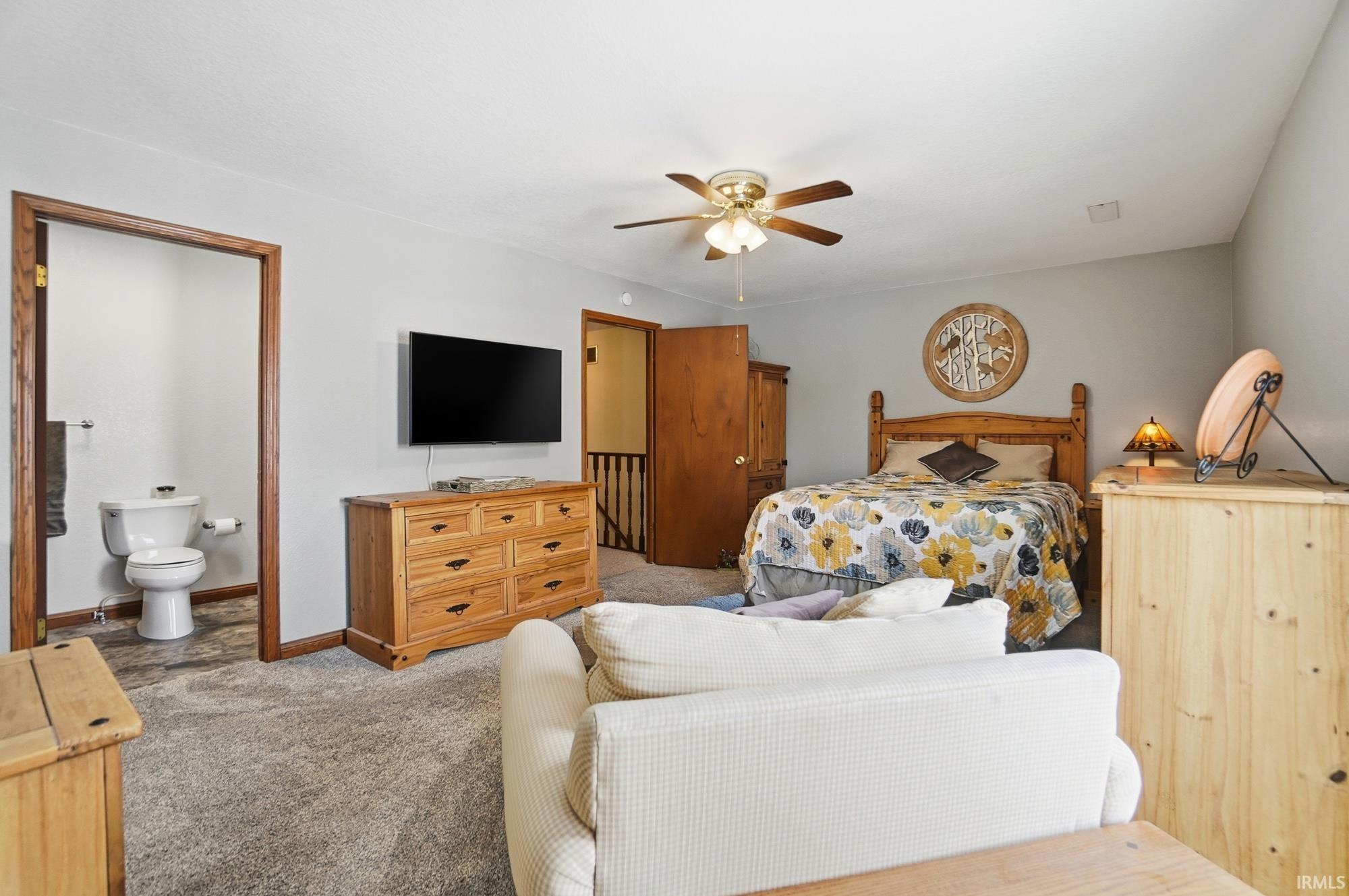 Bedroom with carpet floors, a ceiling fan, and connected bathroom