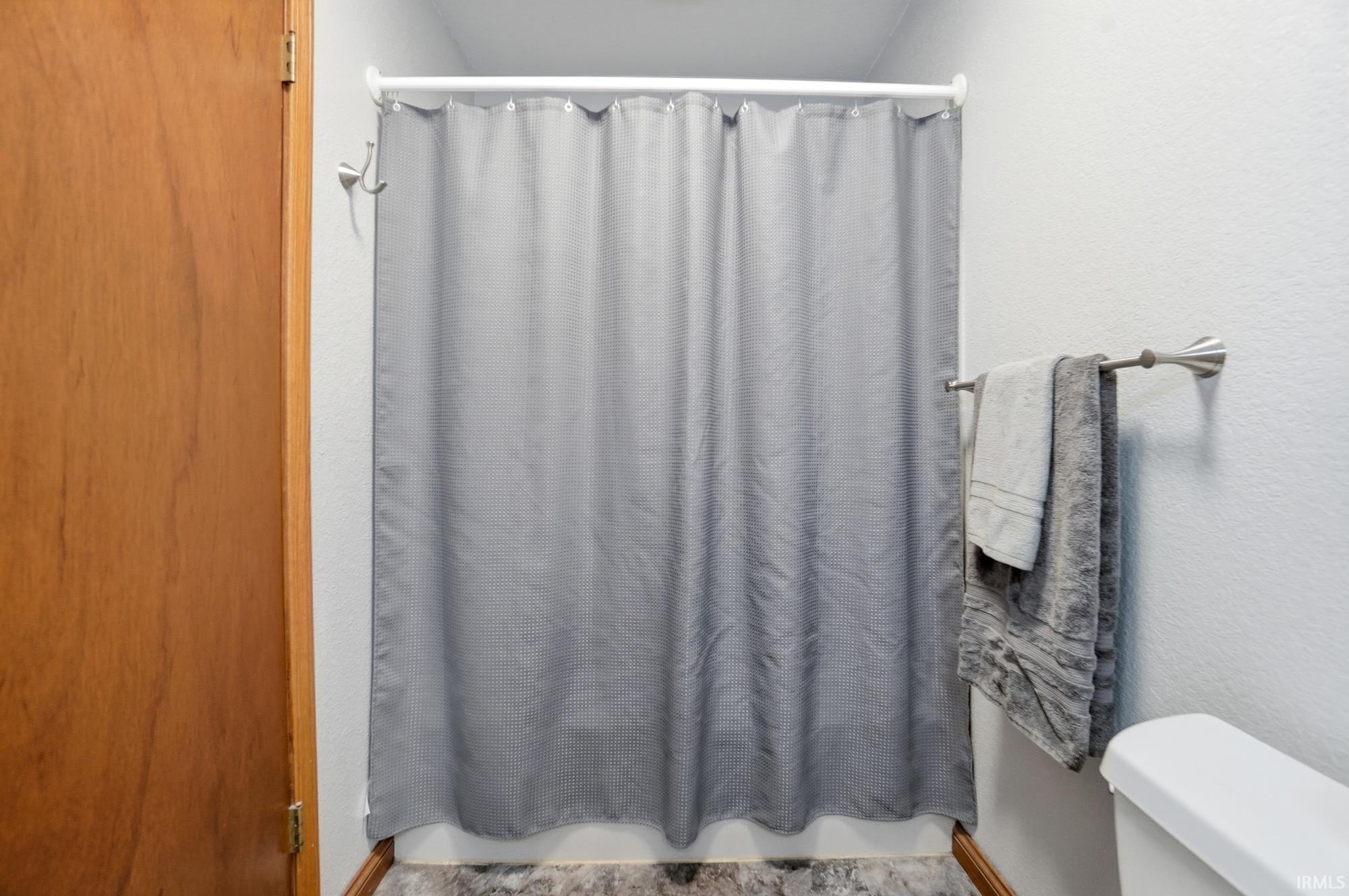 Bathroom featuring a shower with shower curtain and a textured wall