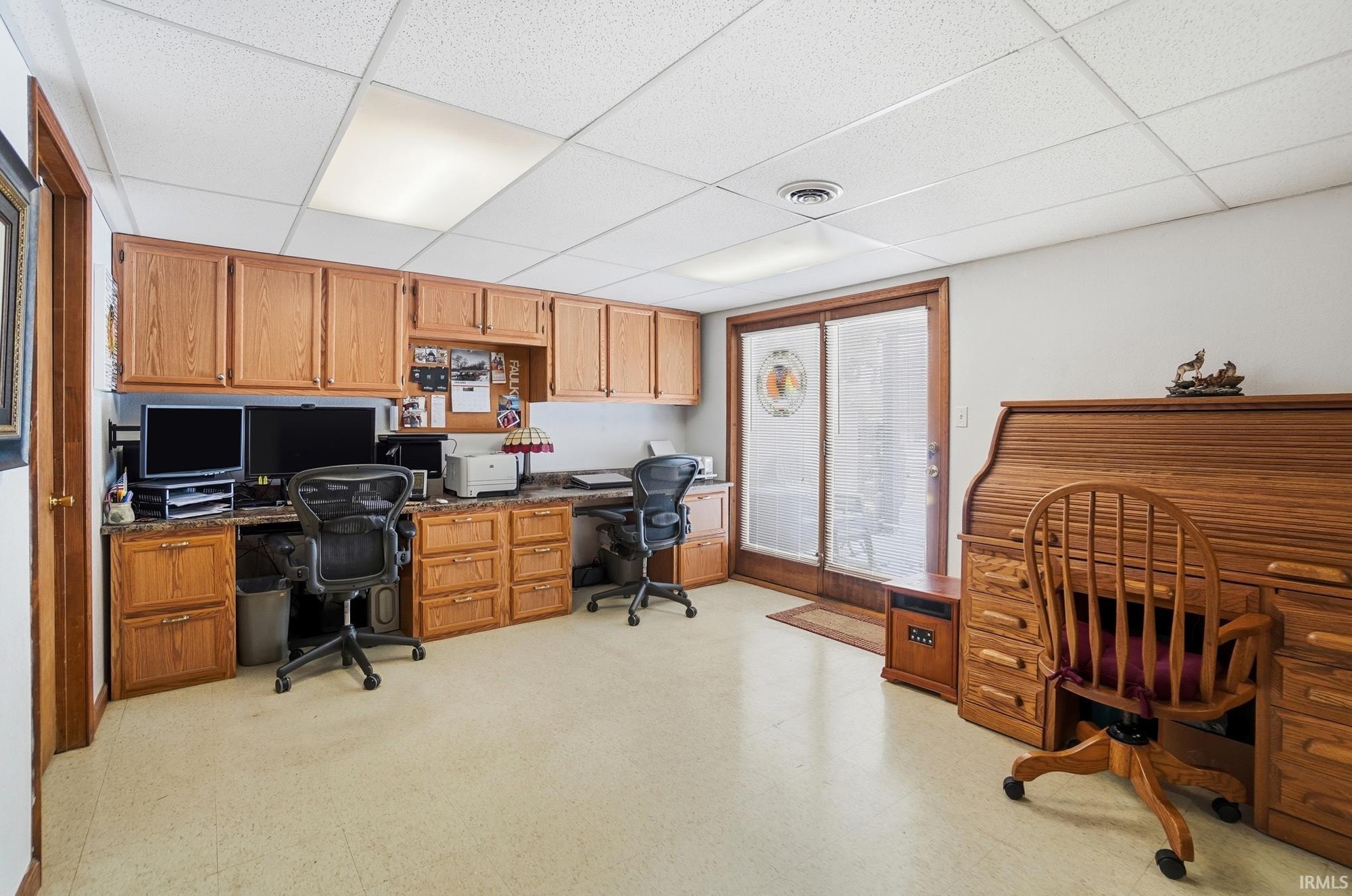 Office area featuring light floors, a drop ceiling, and built in study area