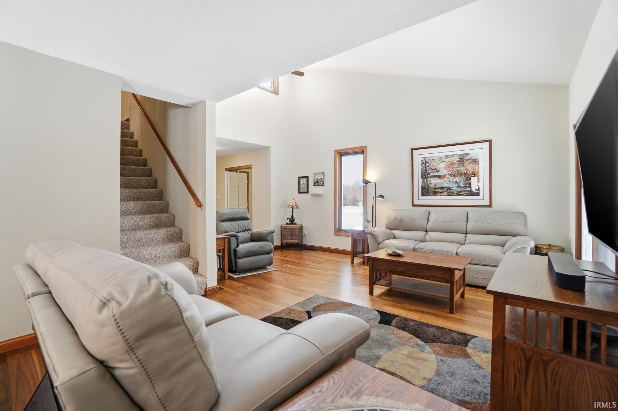 Living room with light wood-style floors and vaulted ceiling