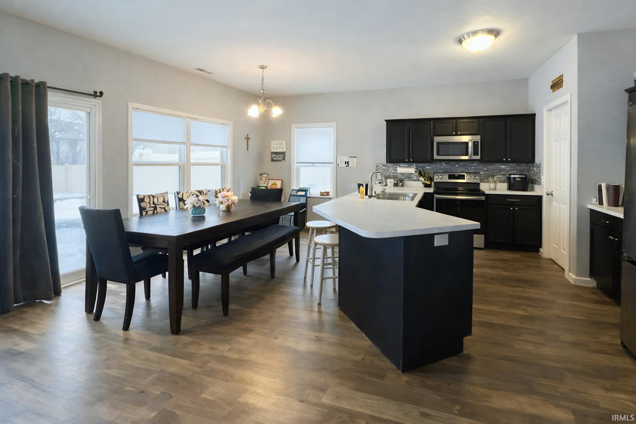 Kitchen with dark cabinetry, light countertops, stainless steel appliances, and backsplash