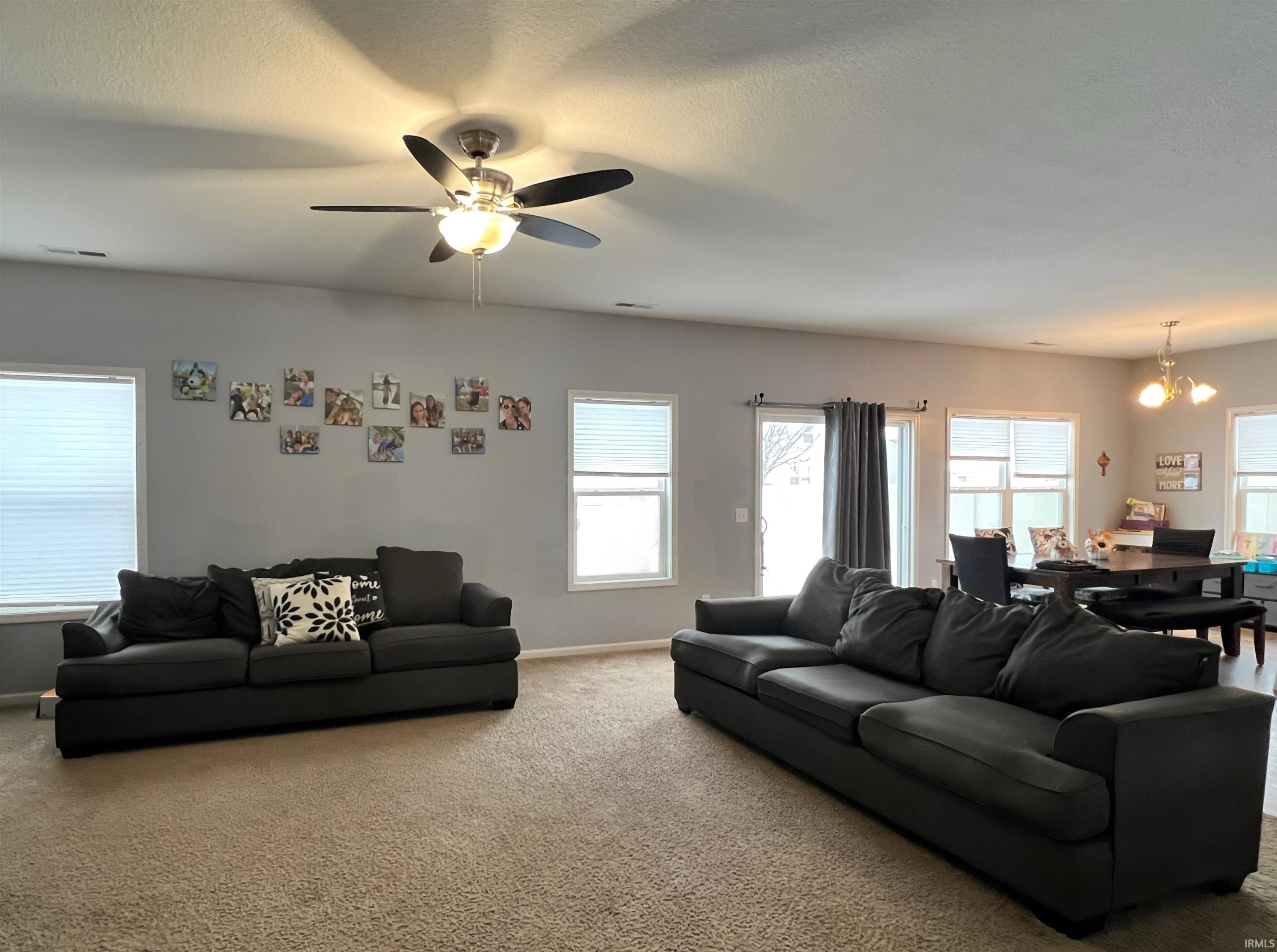 Living area featuring a chandelier, carpet flooring, and ceiling fan
