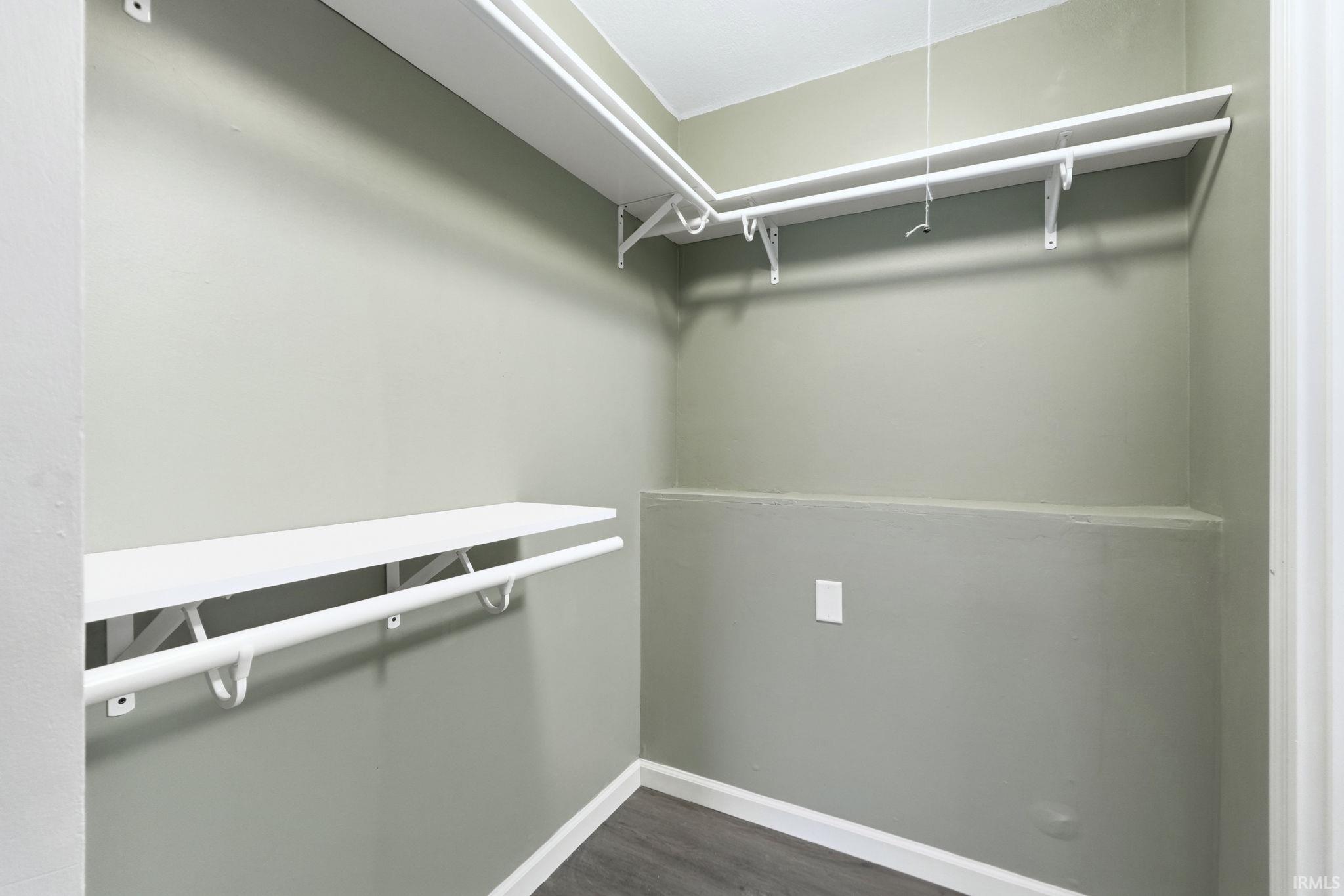 Walk in closet with dark wood-type flooring