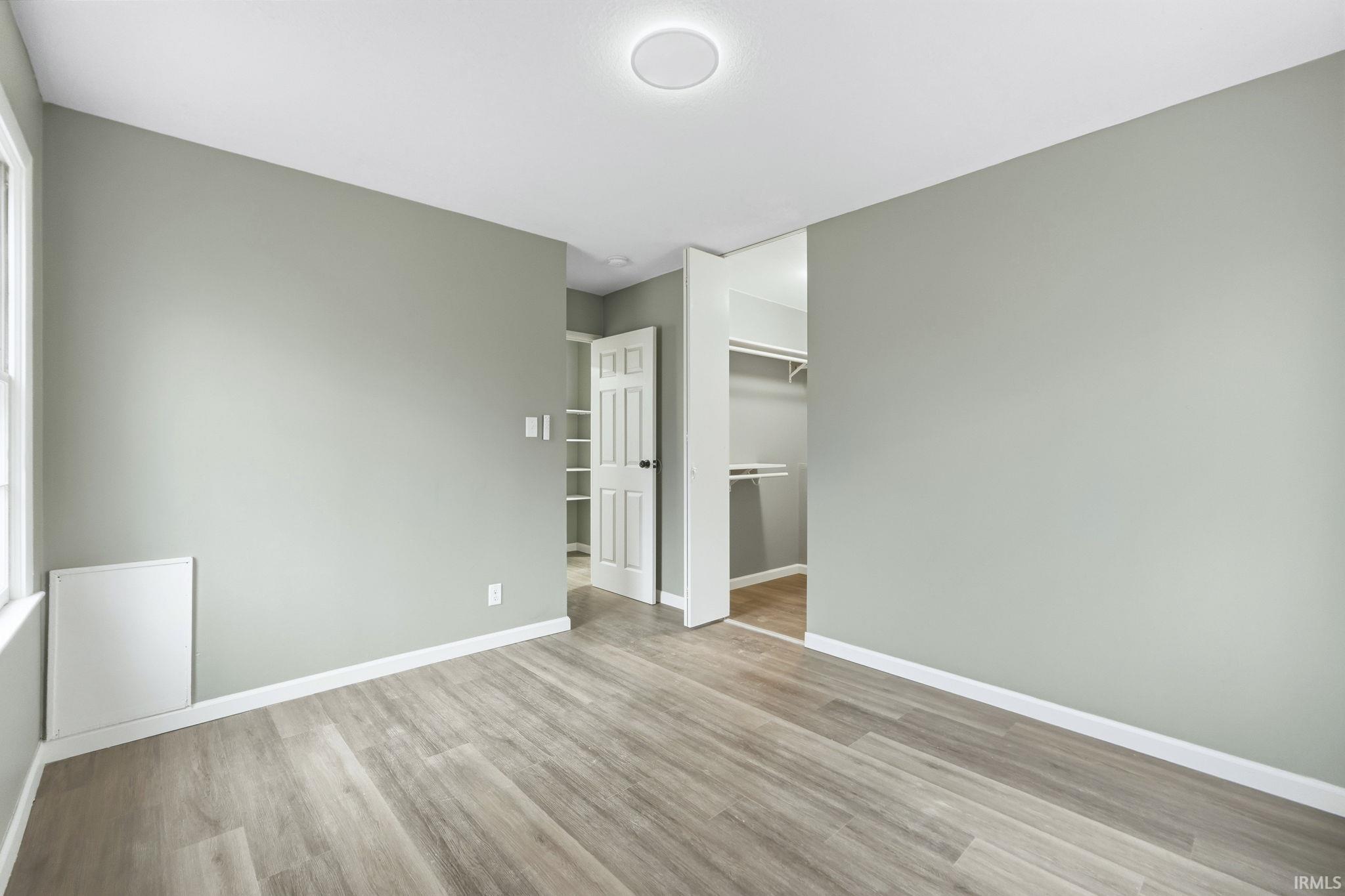 Unfurnished bedroom with a walk in closet and light wood-style floors