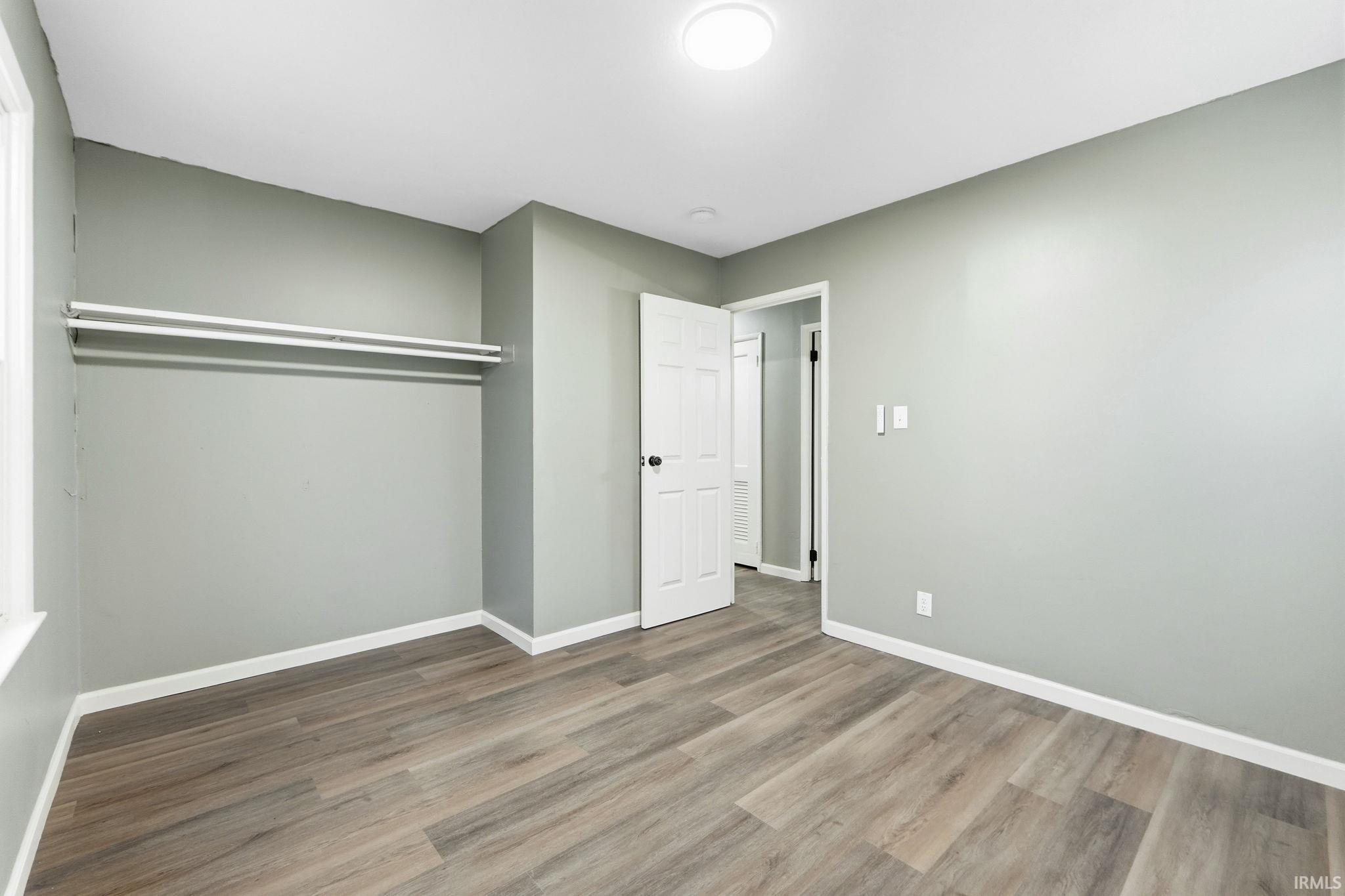 Unfurnished bedroom featuring wood finished floors and baseboards