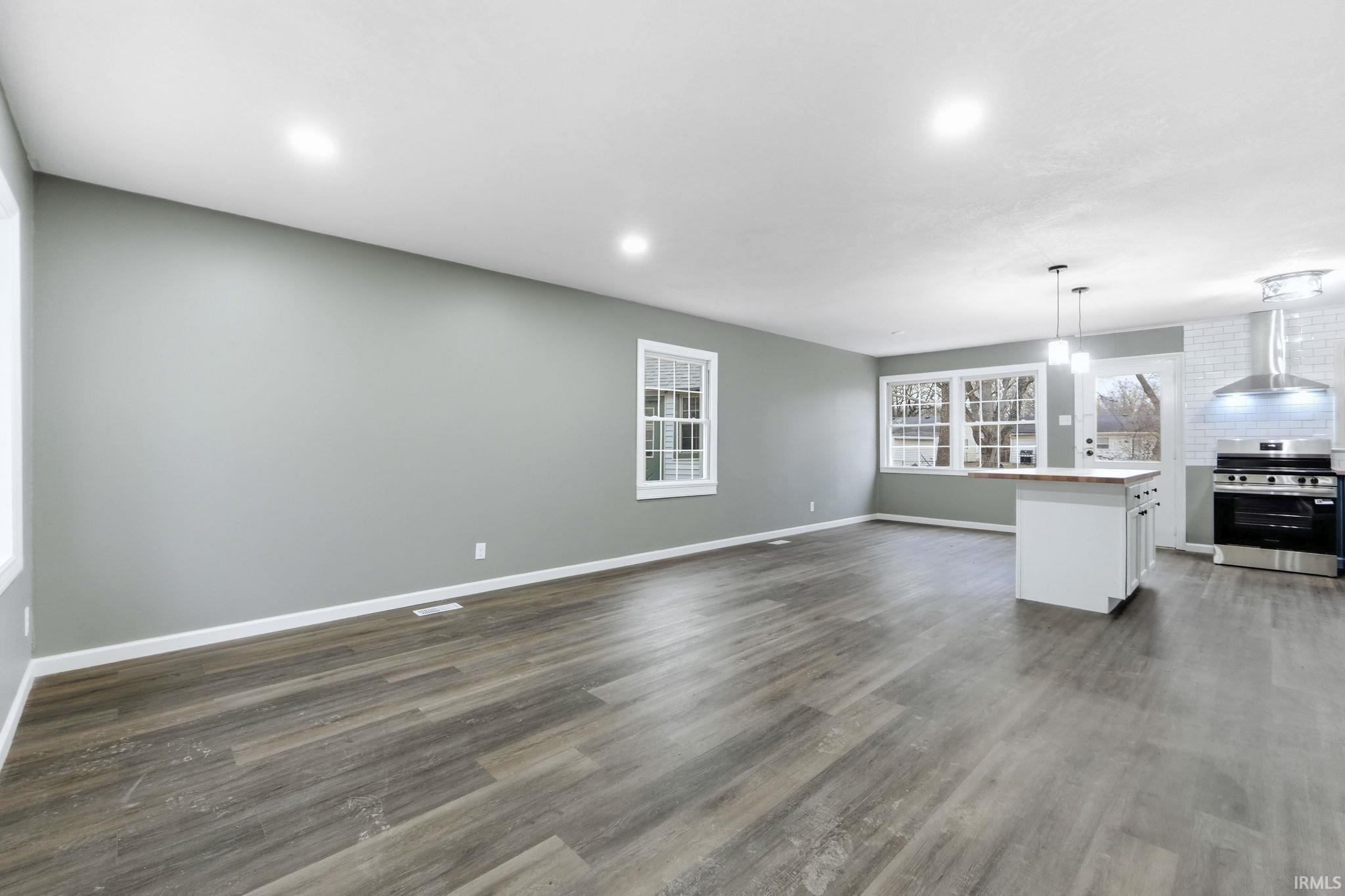 Unfurnished living room with dark wood-style flooring and recessed lighting