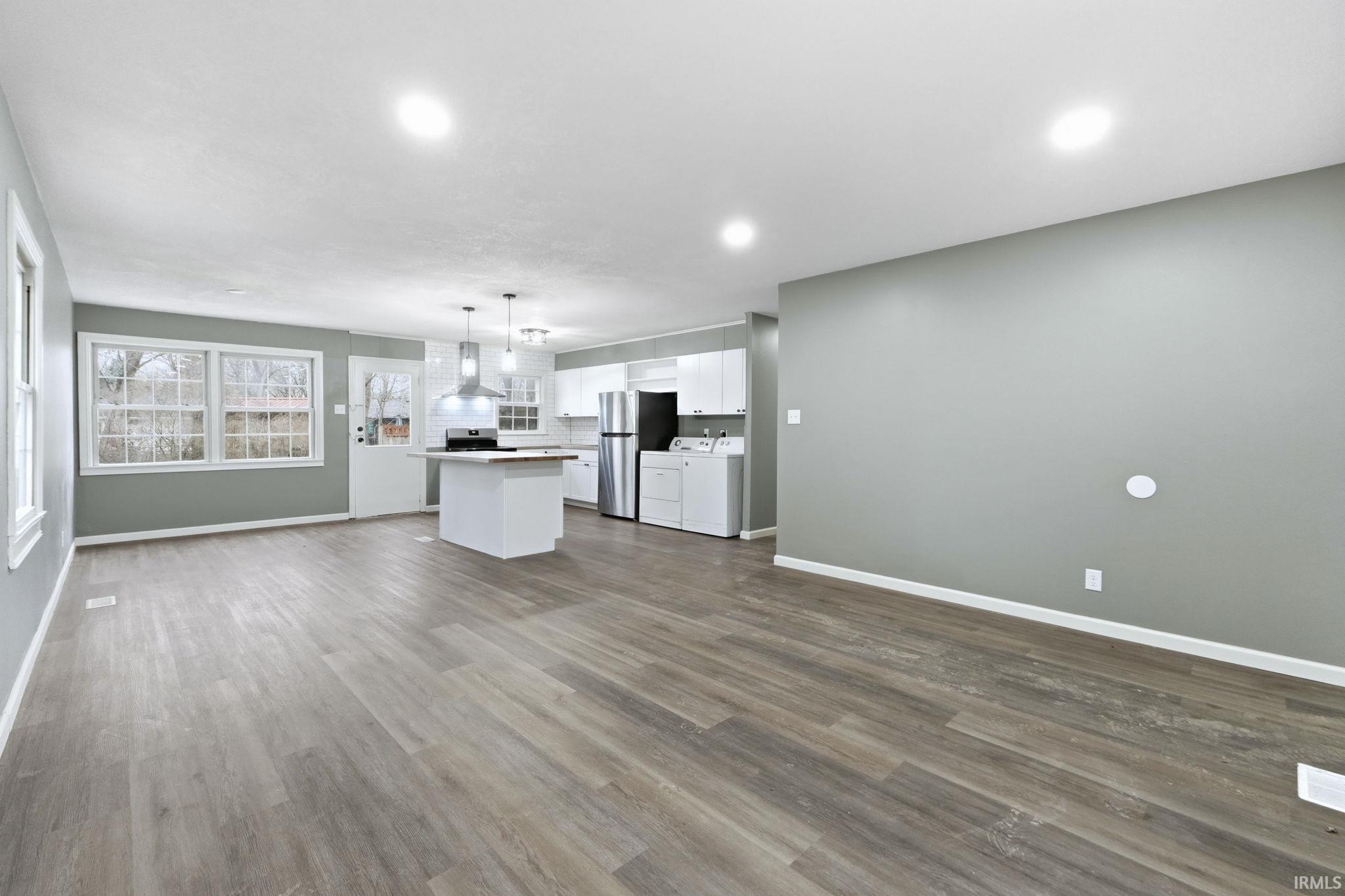 Kitchen with open floor plan, white cabinetry, a center island, hanging light fixtures, and light countertops