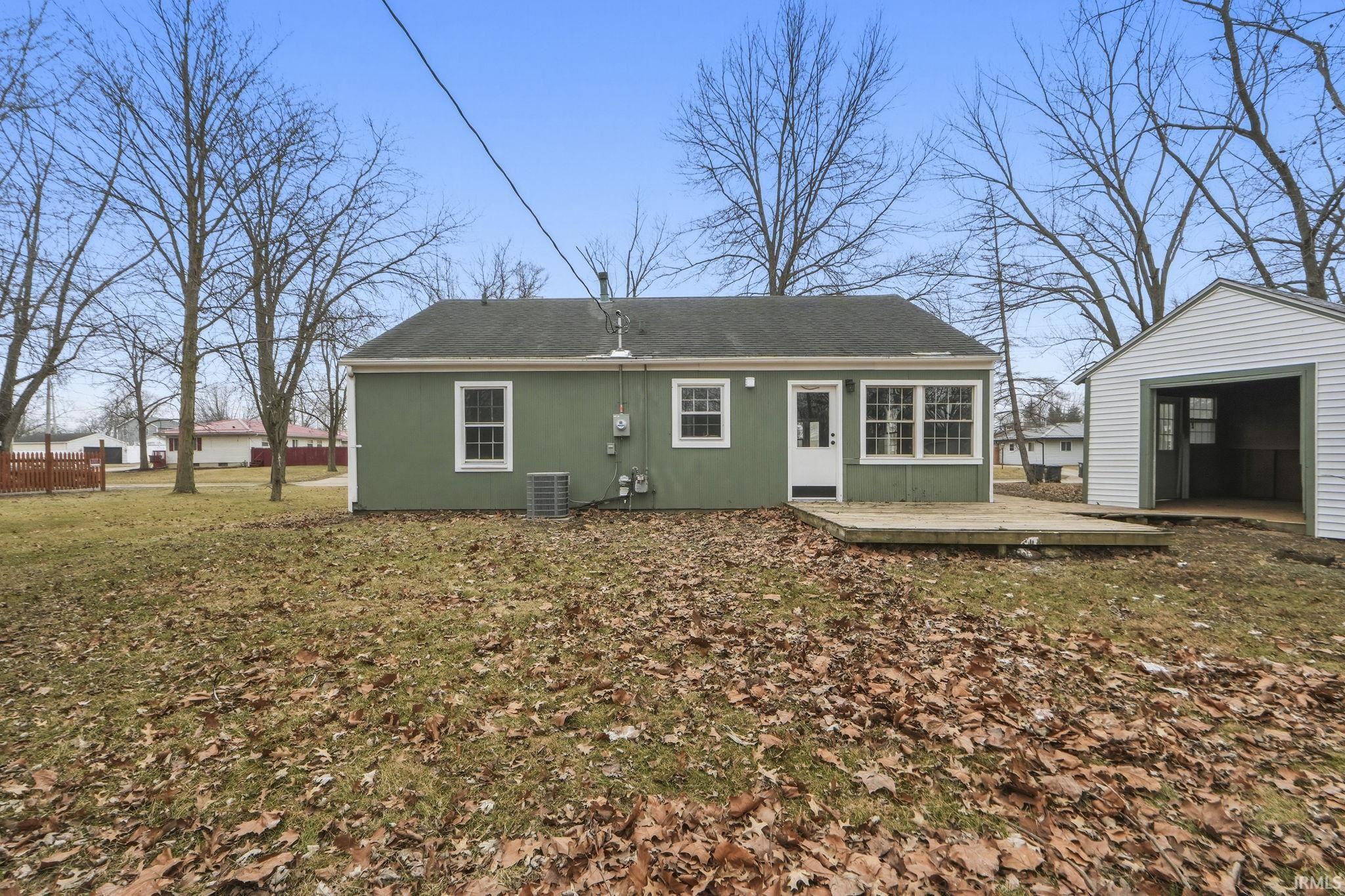 Rear view of property with an outbuilding, roof with shingles, and a garage