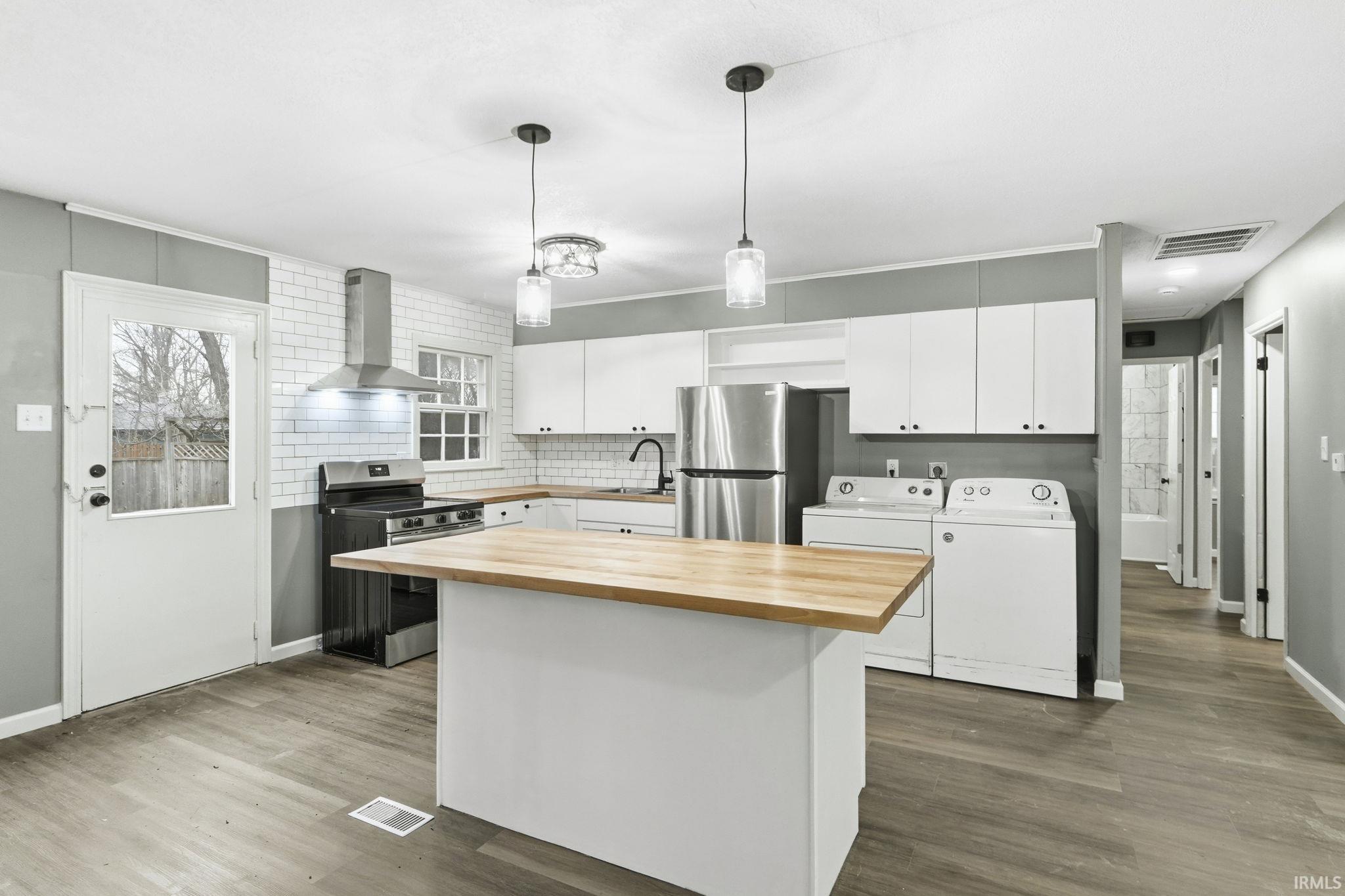 Kitchen featuring a center island, white cabinetry, wood counters, stainless steel appliances, and backsplash