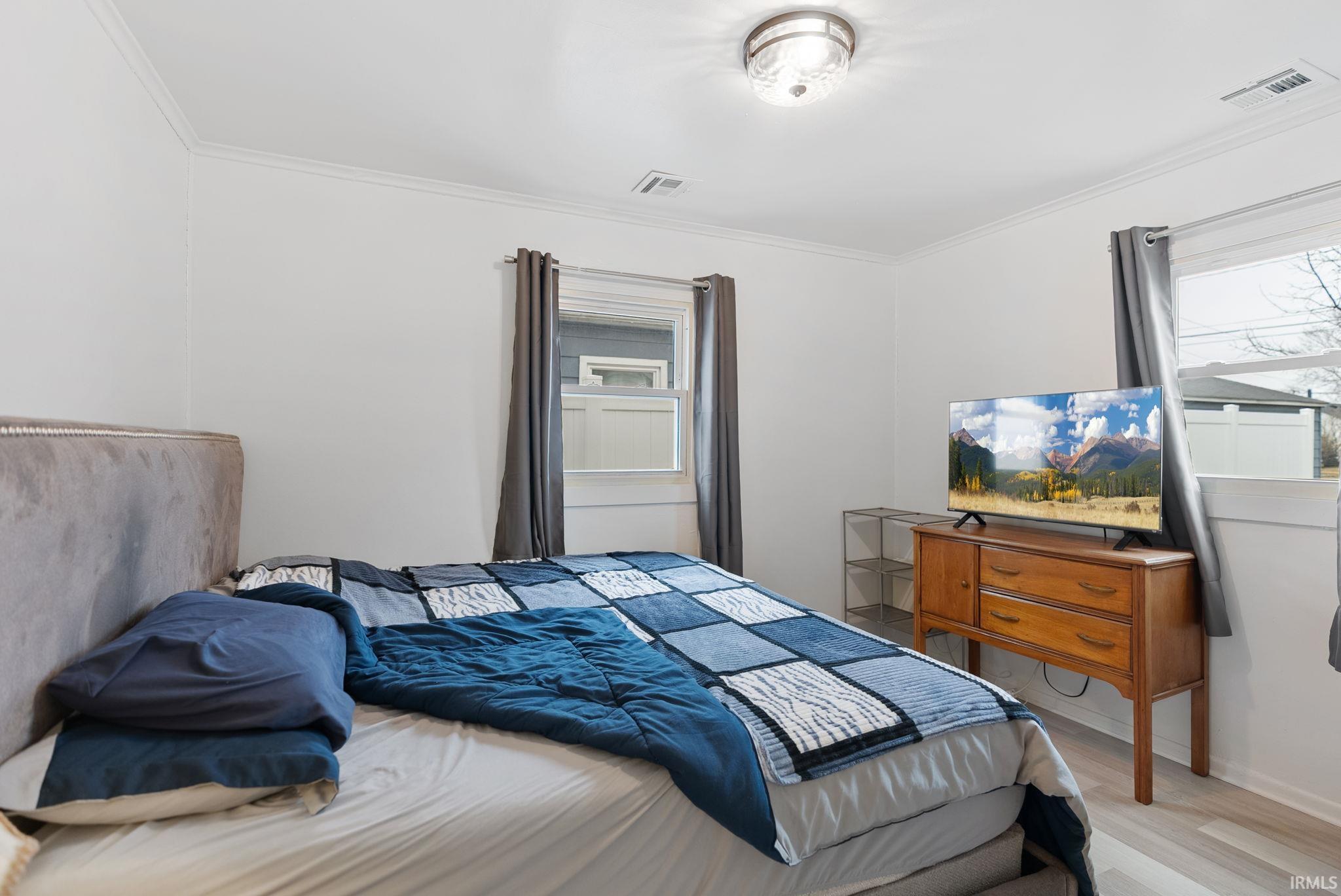 Bedroom featuring light wood-style flooring and crown molding