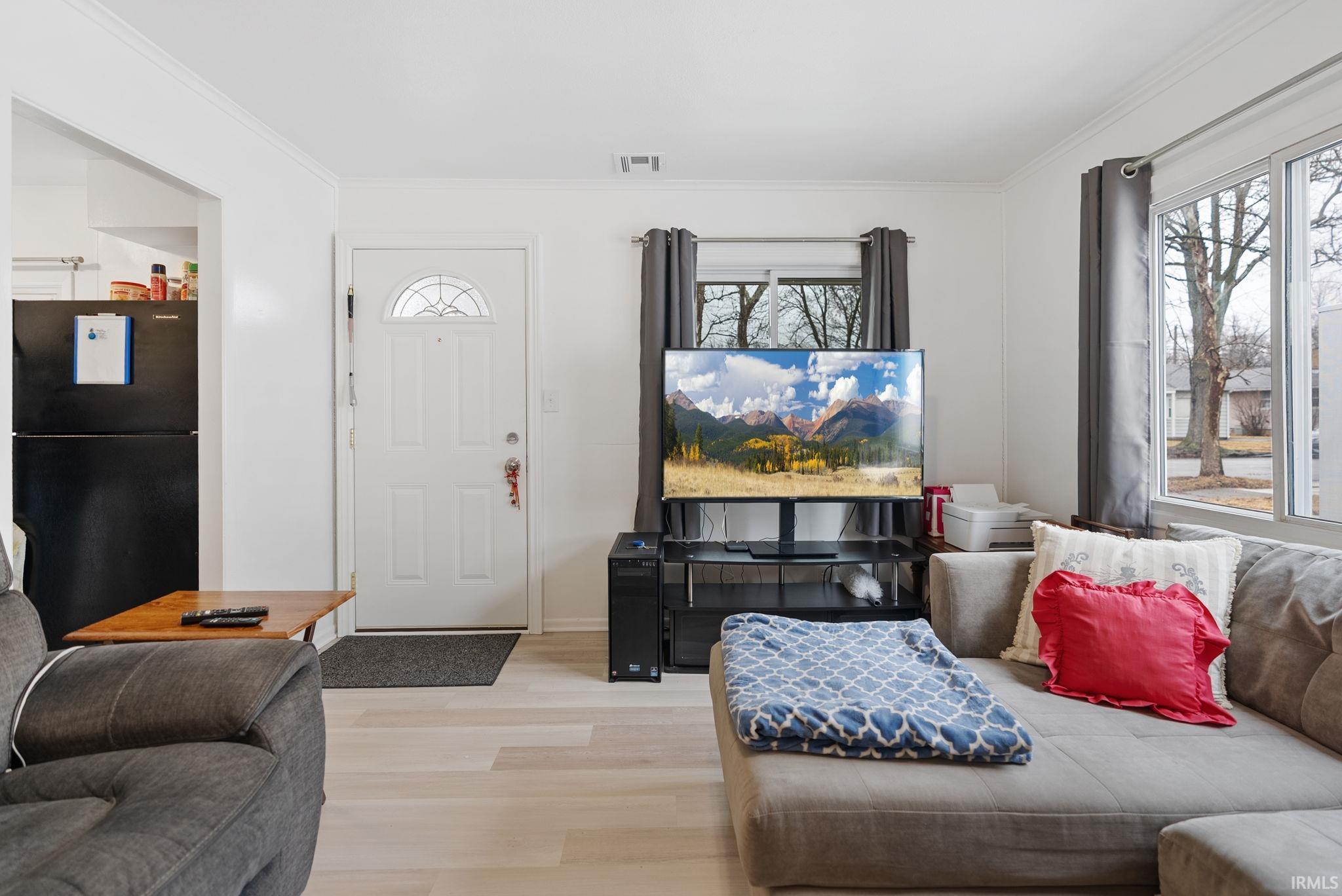 Living room featuring light wood-style flooring and crown molding