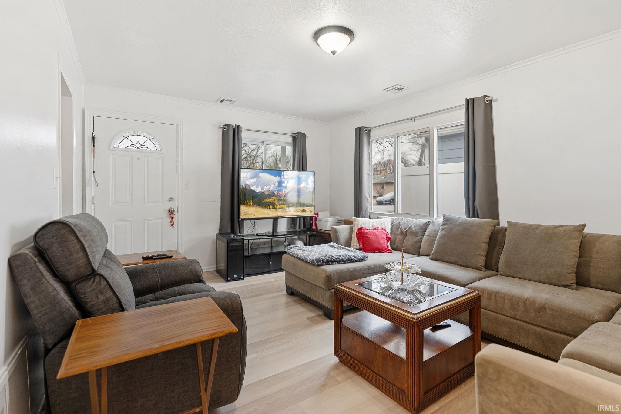 Living room with light wood-type flooring and ornamental molding