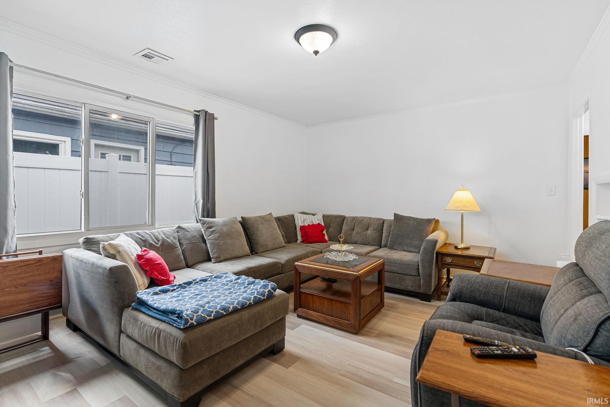 Living area with light wood finished floors and crown molding