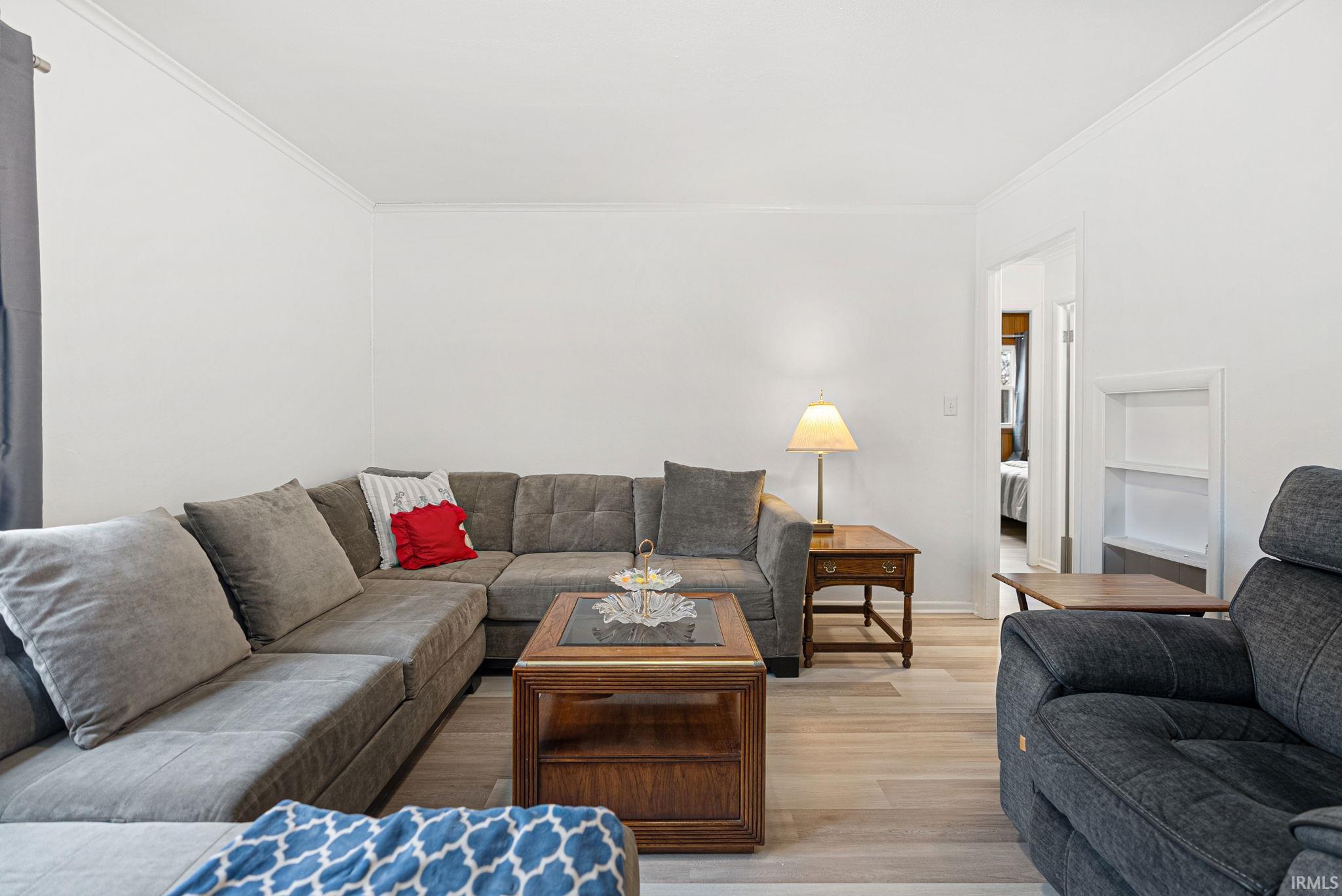 Living area featuring light wood finished floors and crown molding