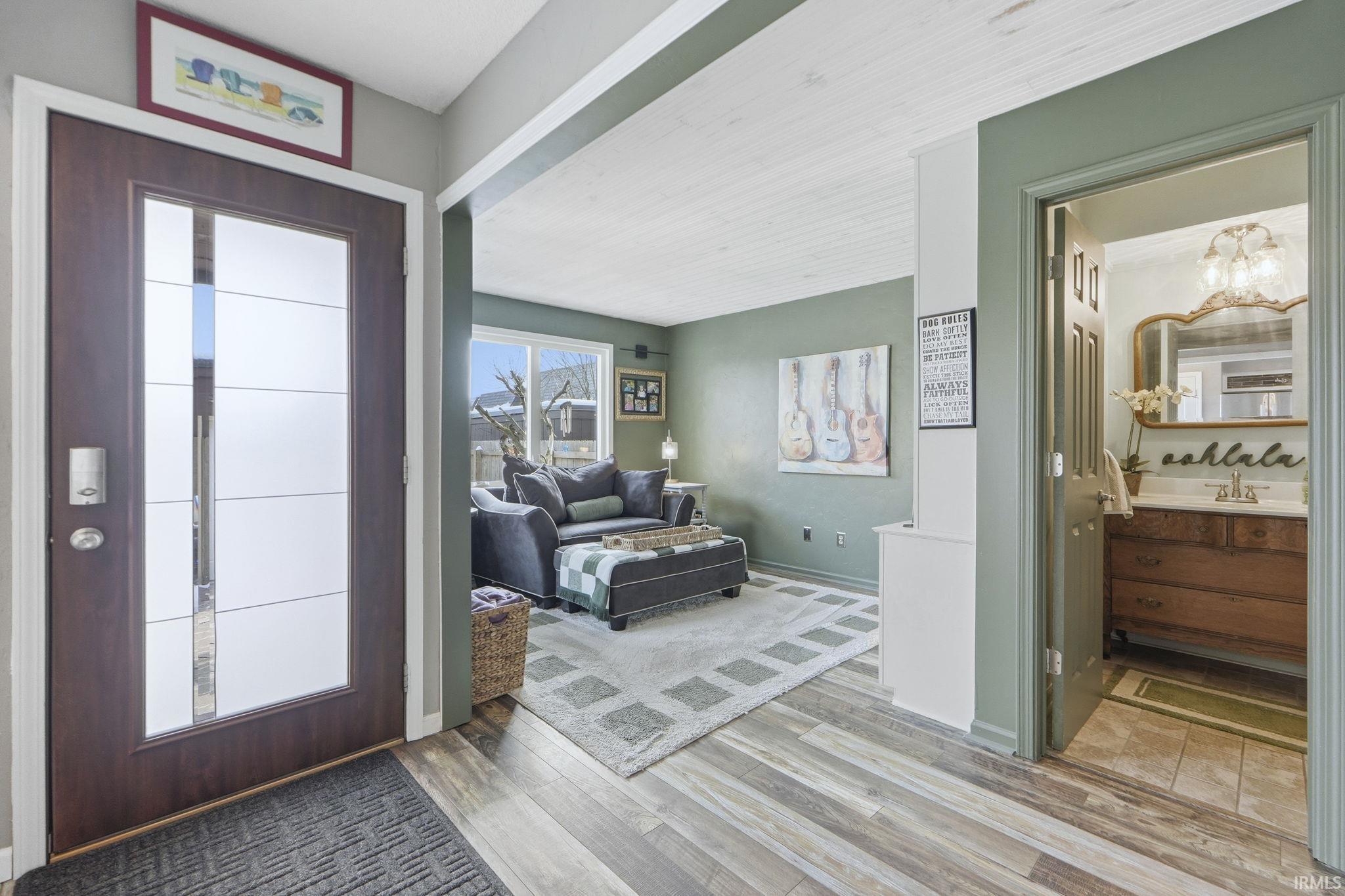 Foyer entrance with light wood finished floors and a chandelier