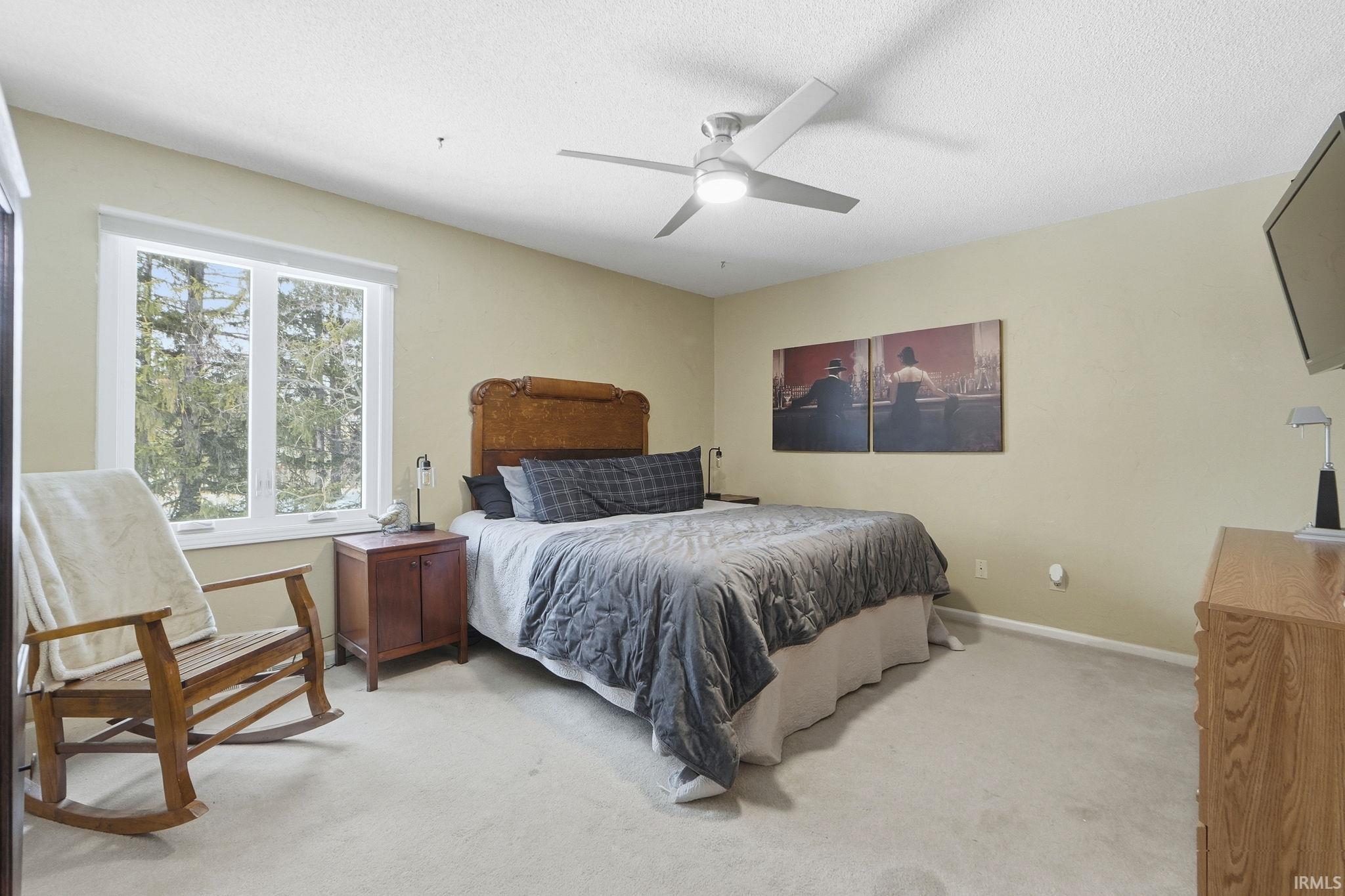 Bedroom with light colored carpet and a ceiling fan