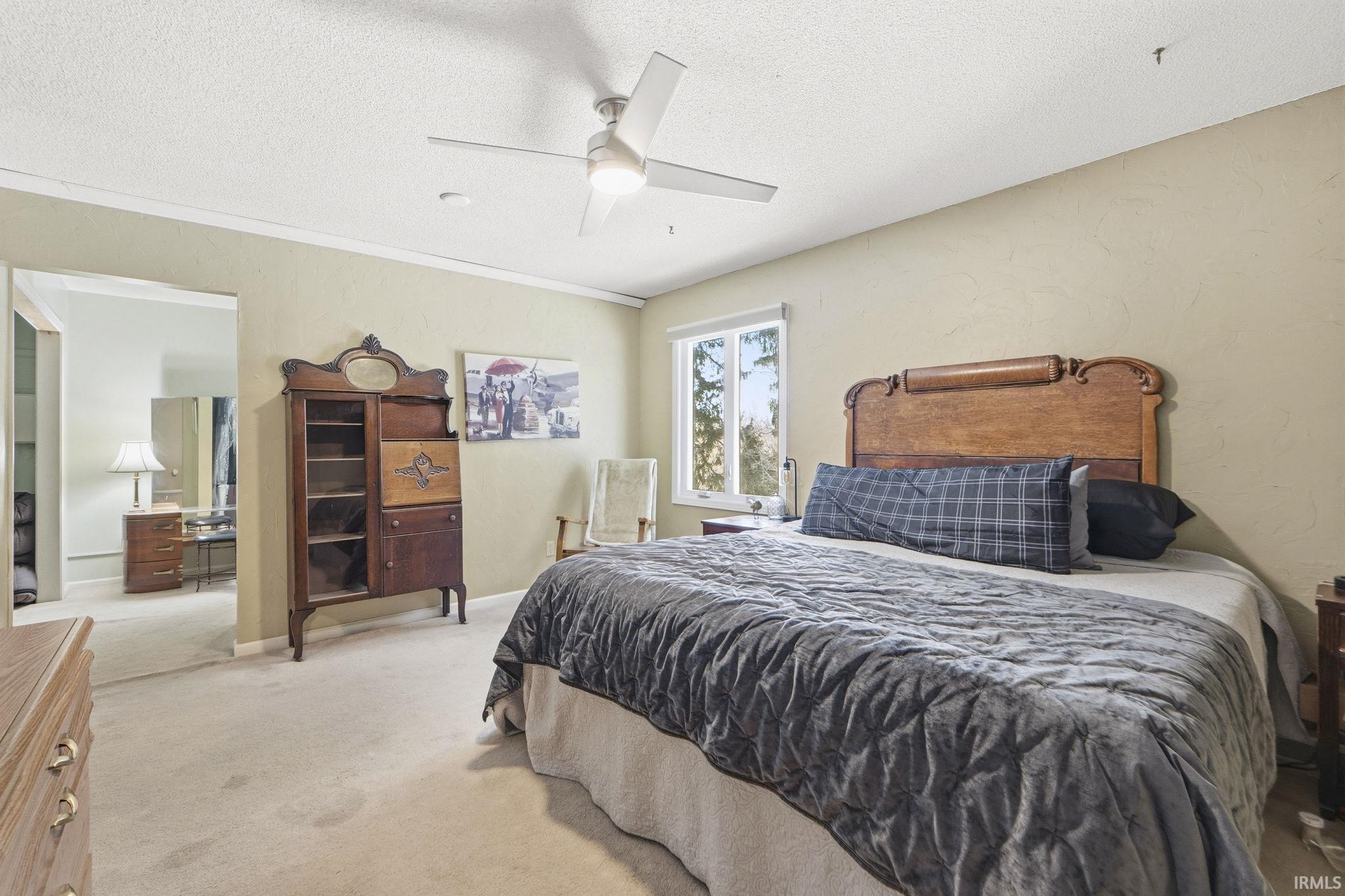 Bedroom featuring carpet, a textured ceiling, a textured wall, and ceiling fan