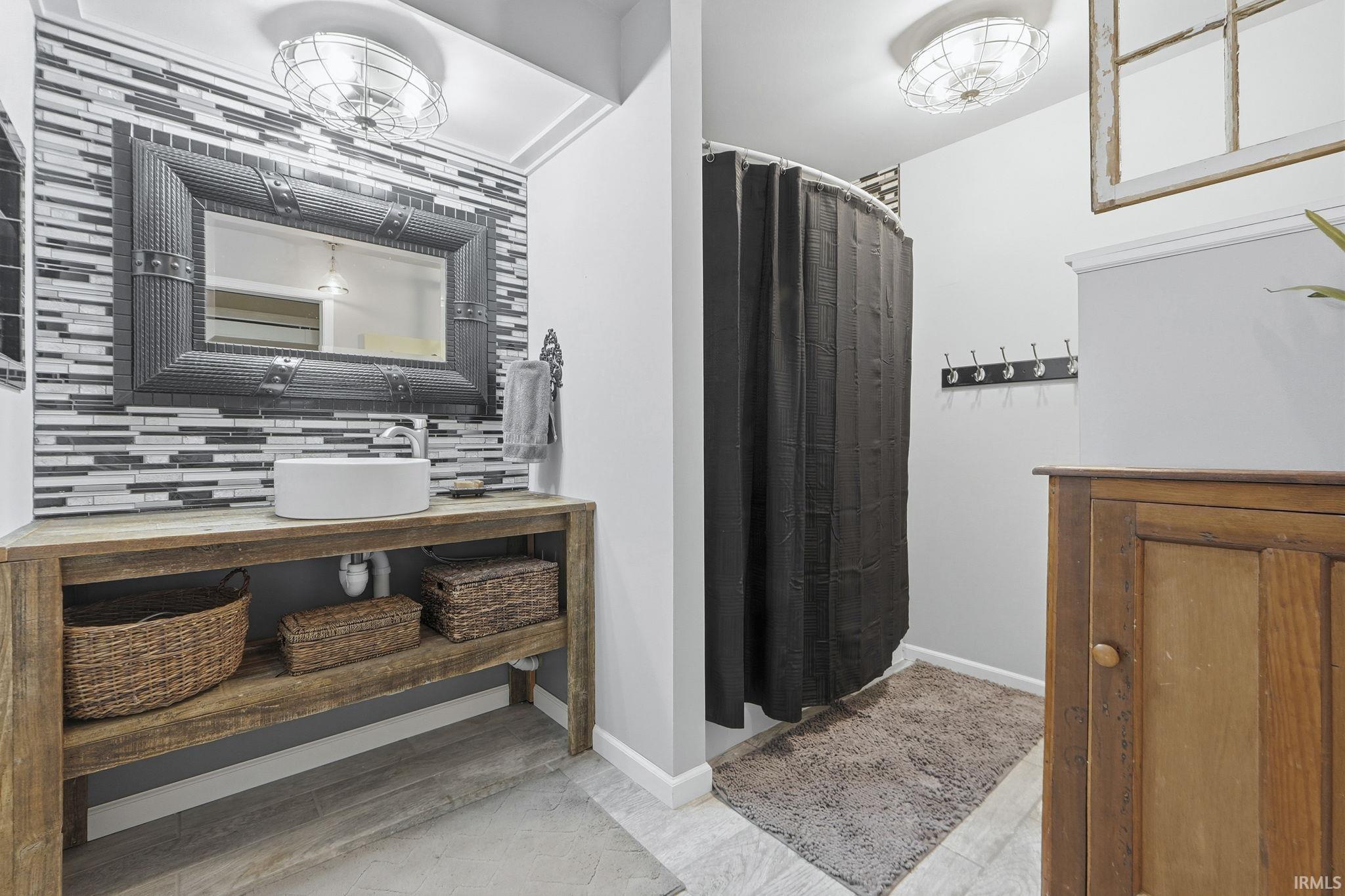 Bathroom with vanity, a shower with shower curtain, and decorative backsplash