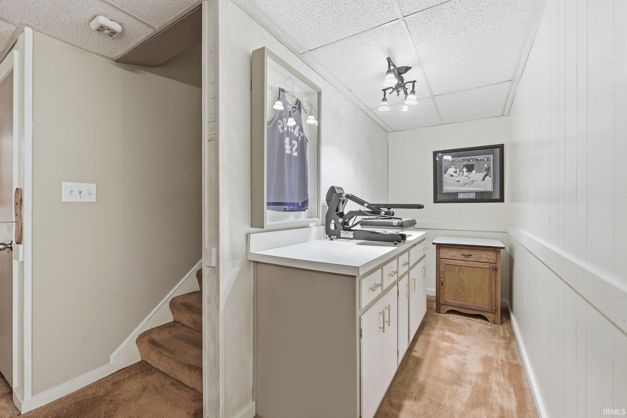 Bar featuring a drop ceiling, light countertops, light carpet, and white cabinets