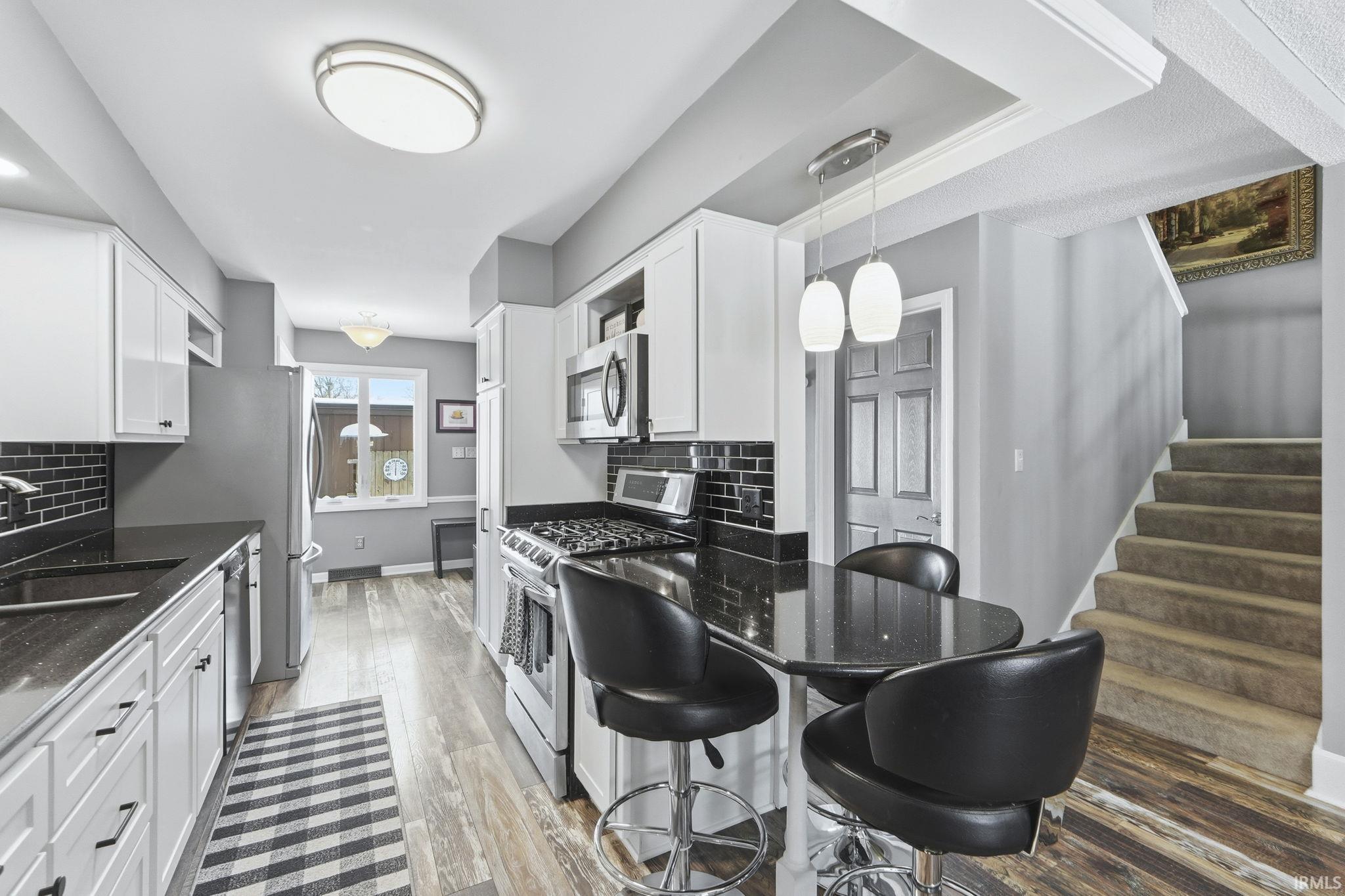 Kitchen featuring dark stone countertops, stainless steel appliances, and white cabinets