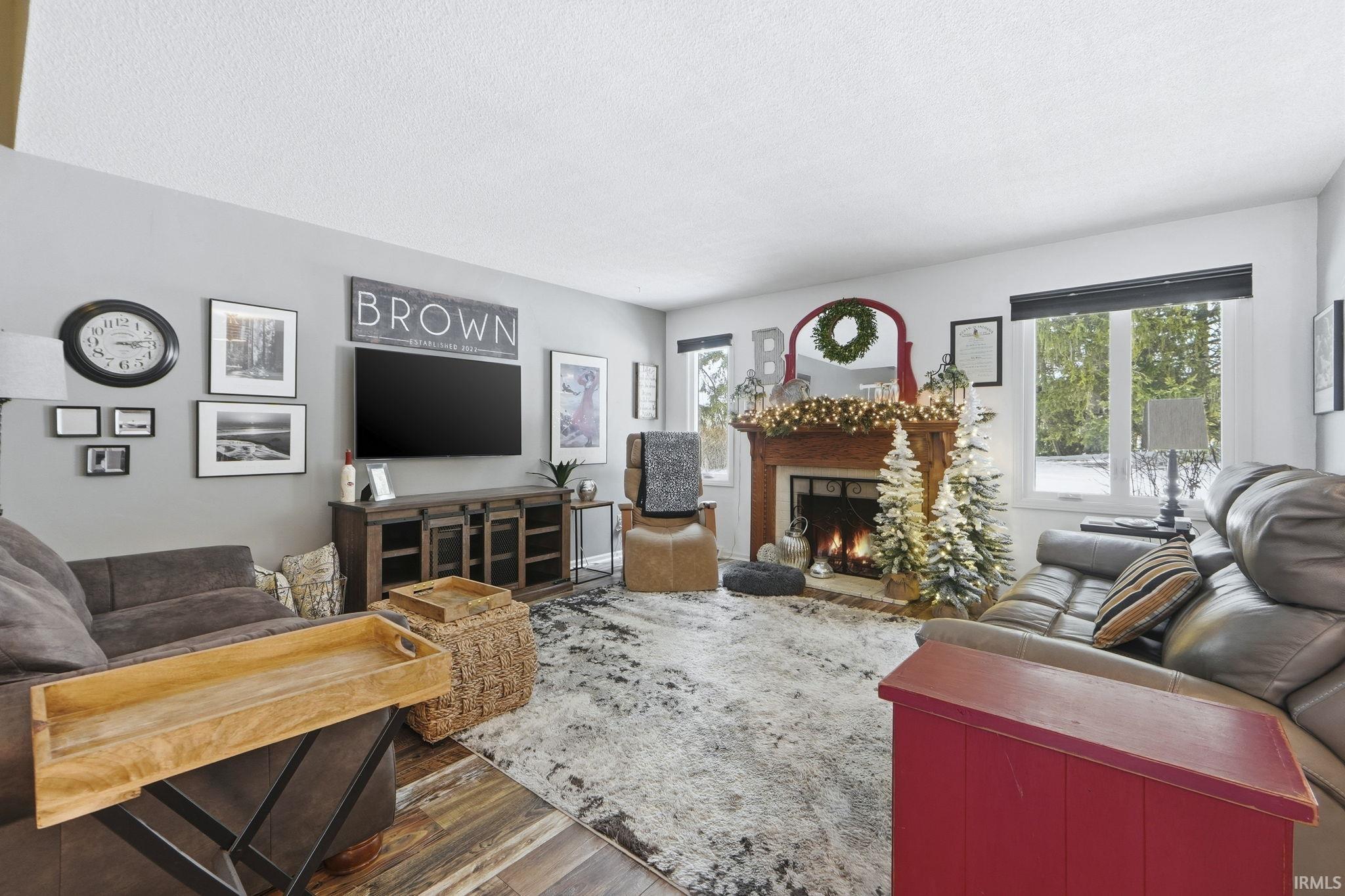Living room featuring wood finished floors, a brick fireplace, and a textured ceiling