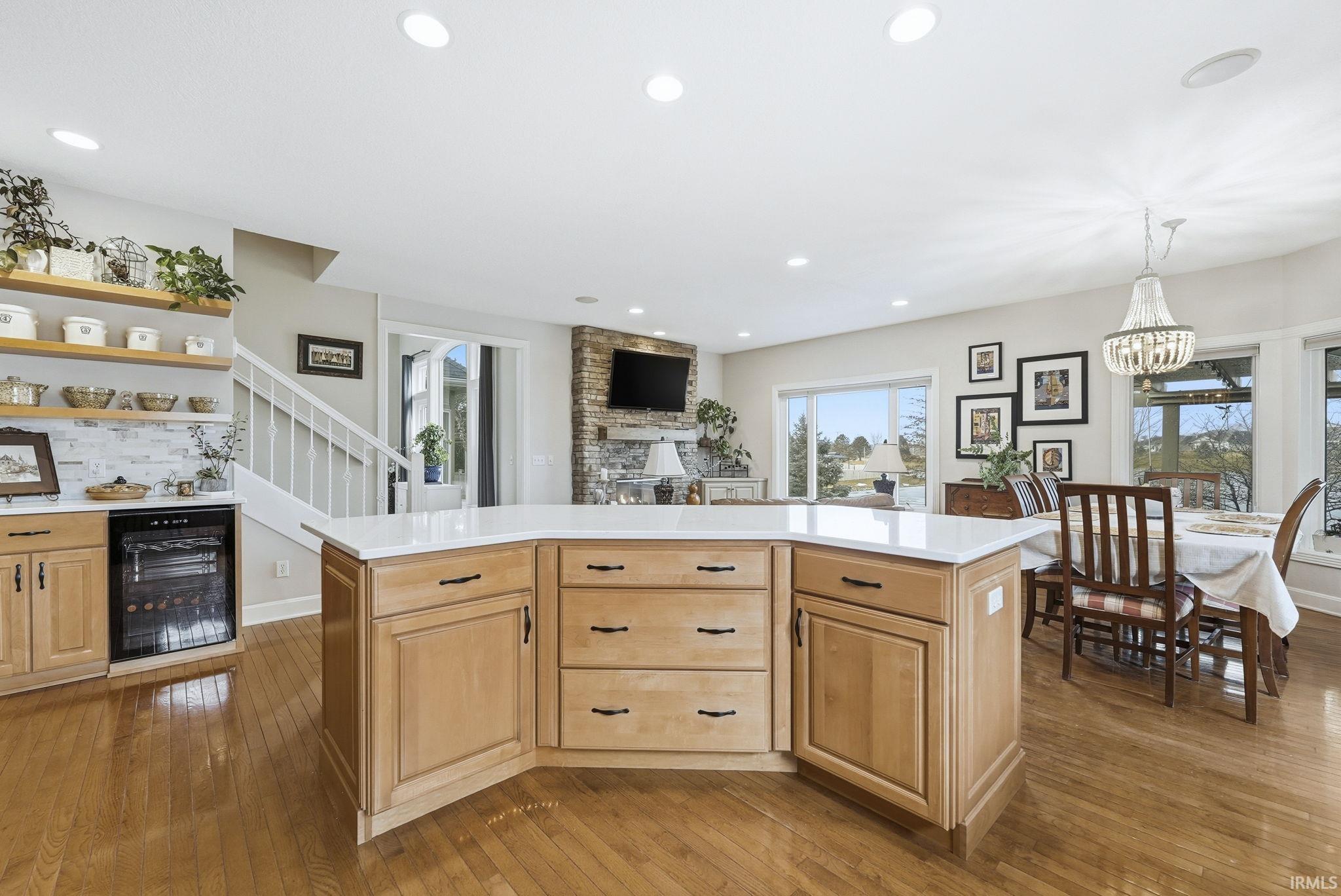 Kitchen featuring wine cooler, a kitchen island, dark wood finished floors, open shelves, and light wood finish cabinets