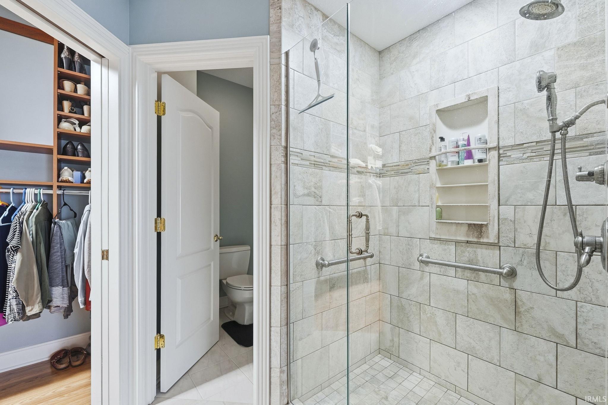 Bathroom featuring a shower stall and a walk in closet