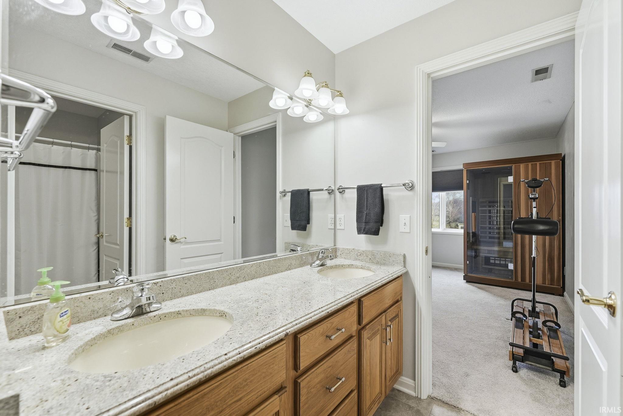 Bathroom with double vanity, a relaxing sauna, a shower with curtain, and light colored carpet