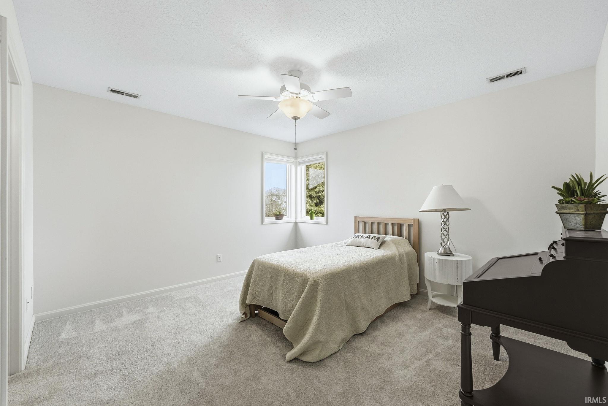 Carpeted bedroom featuring a ceiling fan and a textured ceiling