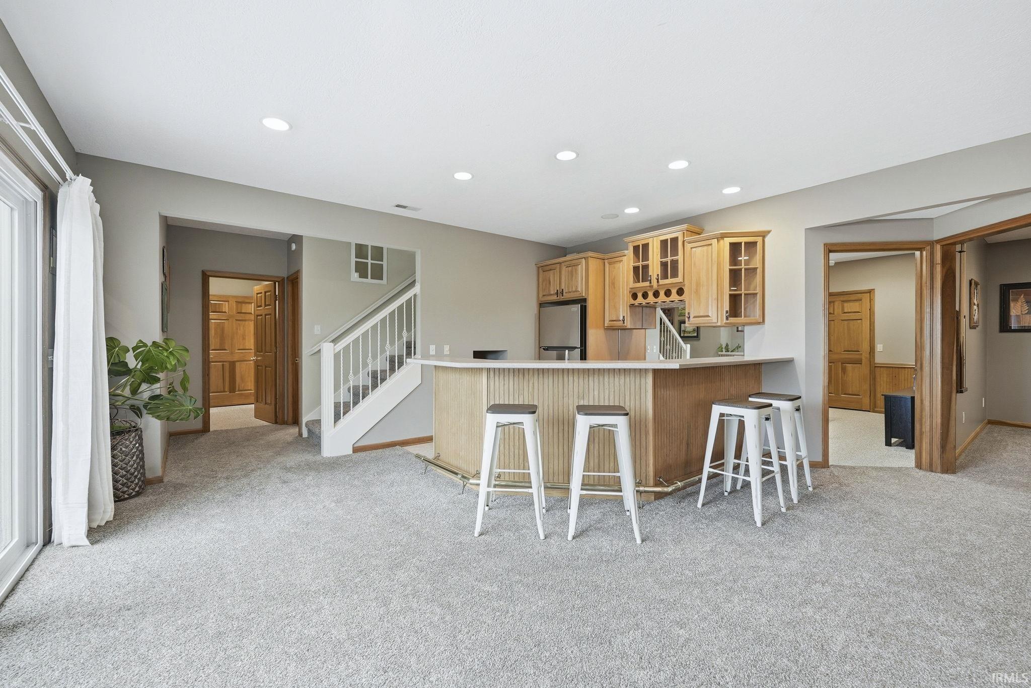 Kitchen with glass fronted cabinets, a breakfast bar area, light colored carpet, recessed lighting, and light countertops