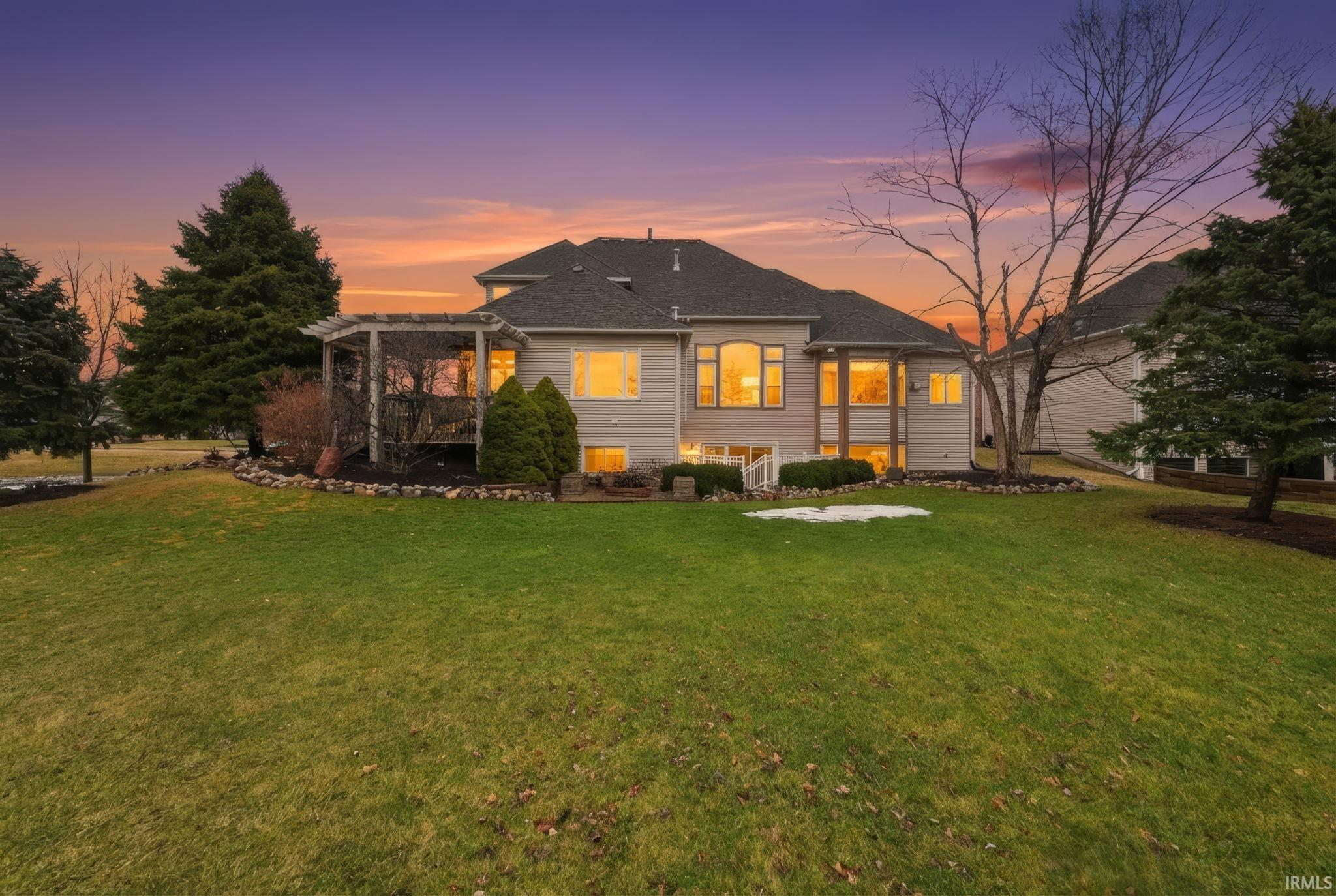 Back of house at dusk with a yard and a pergola