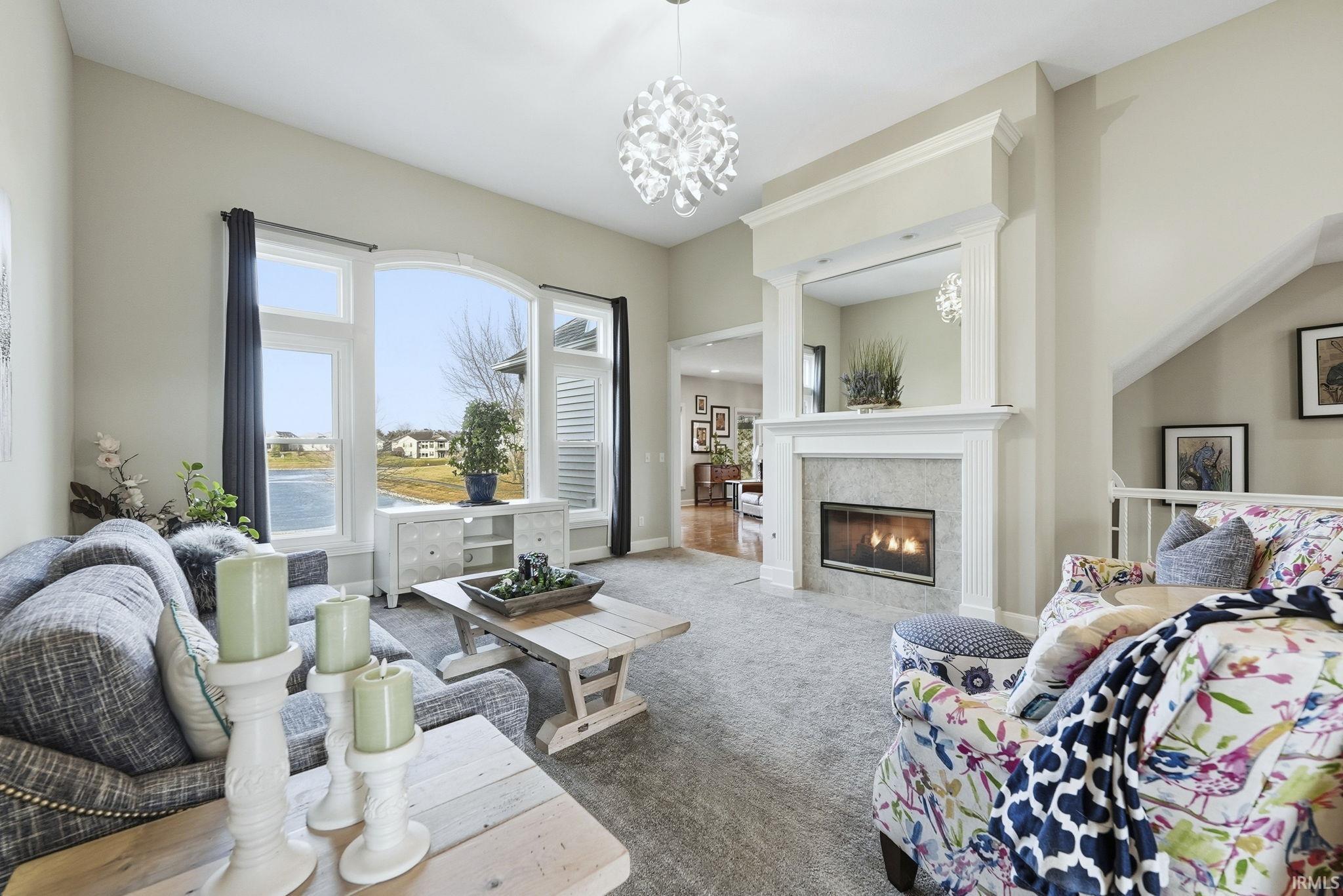 Living area with dark colored carpet, hanging lights, and a tile fireplace