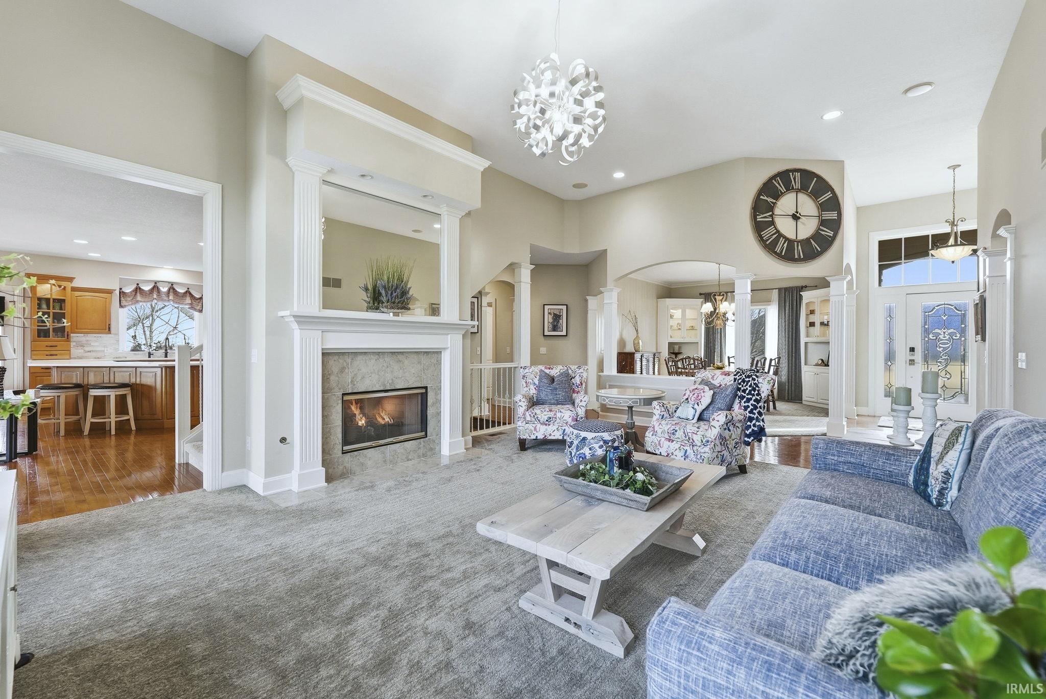 Carpeted living room featuring suspended lighting, a premium fireplace, and arched walkways