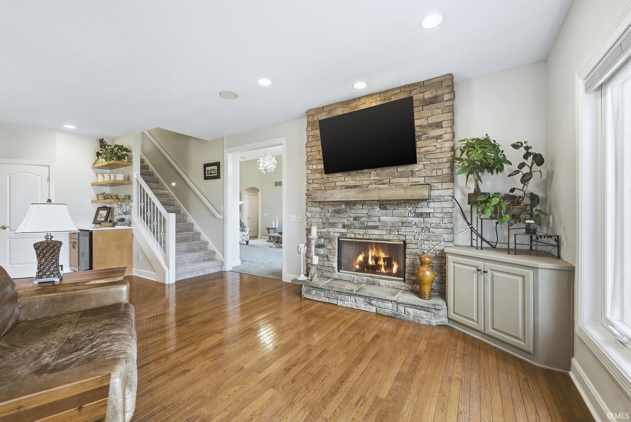 Unfurnished living room with light wood-style flooring, a stone fireplace, and recessed lighting