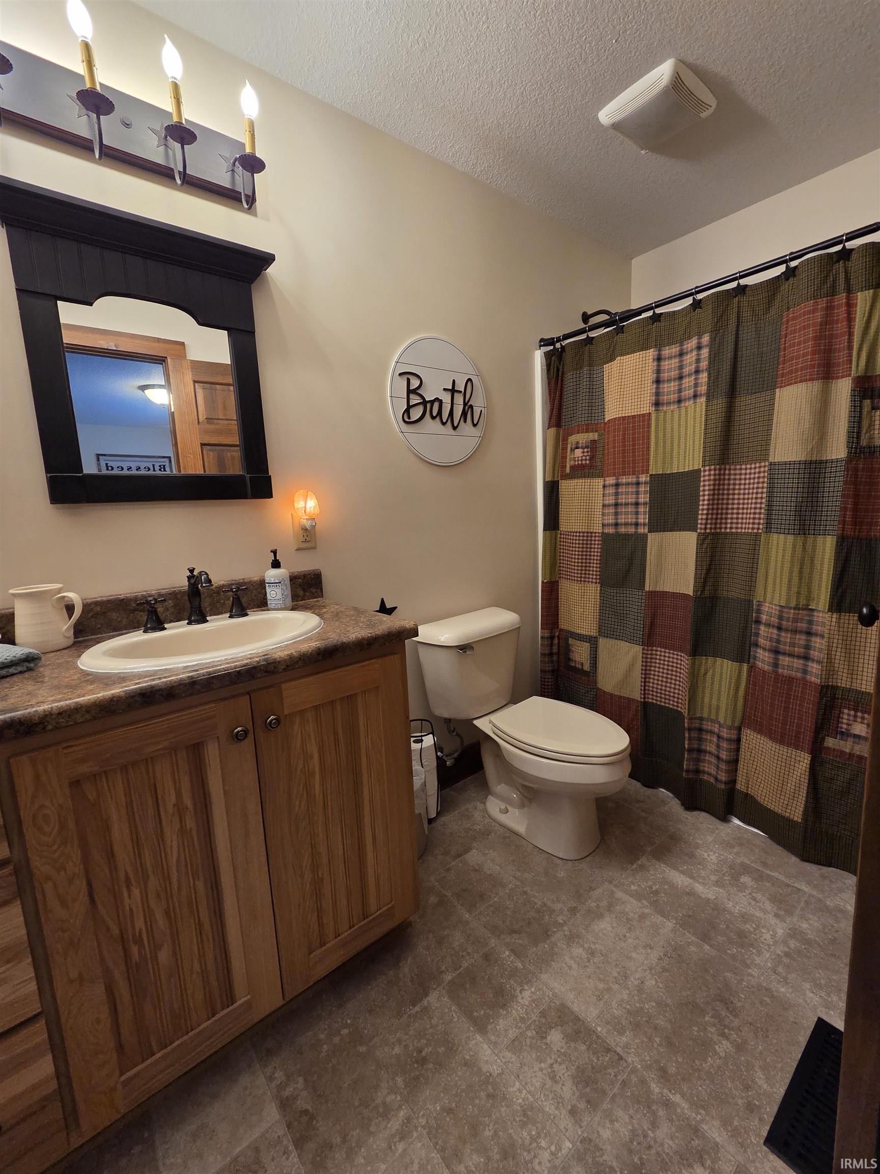 Full bathroom with vanity, a textured ceiling, and a shower with shower curtain