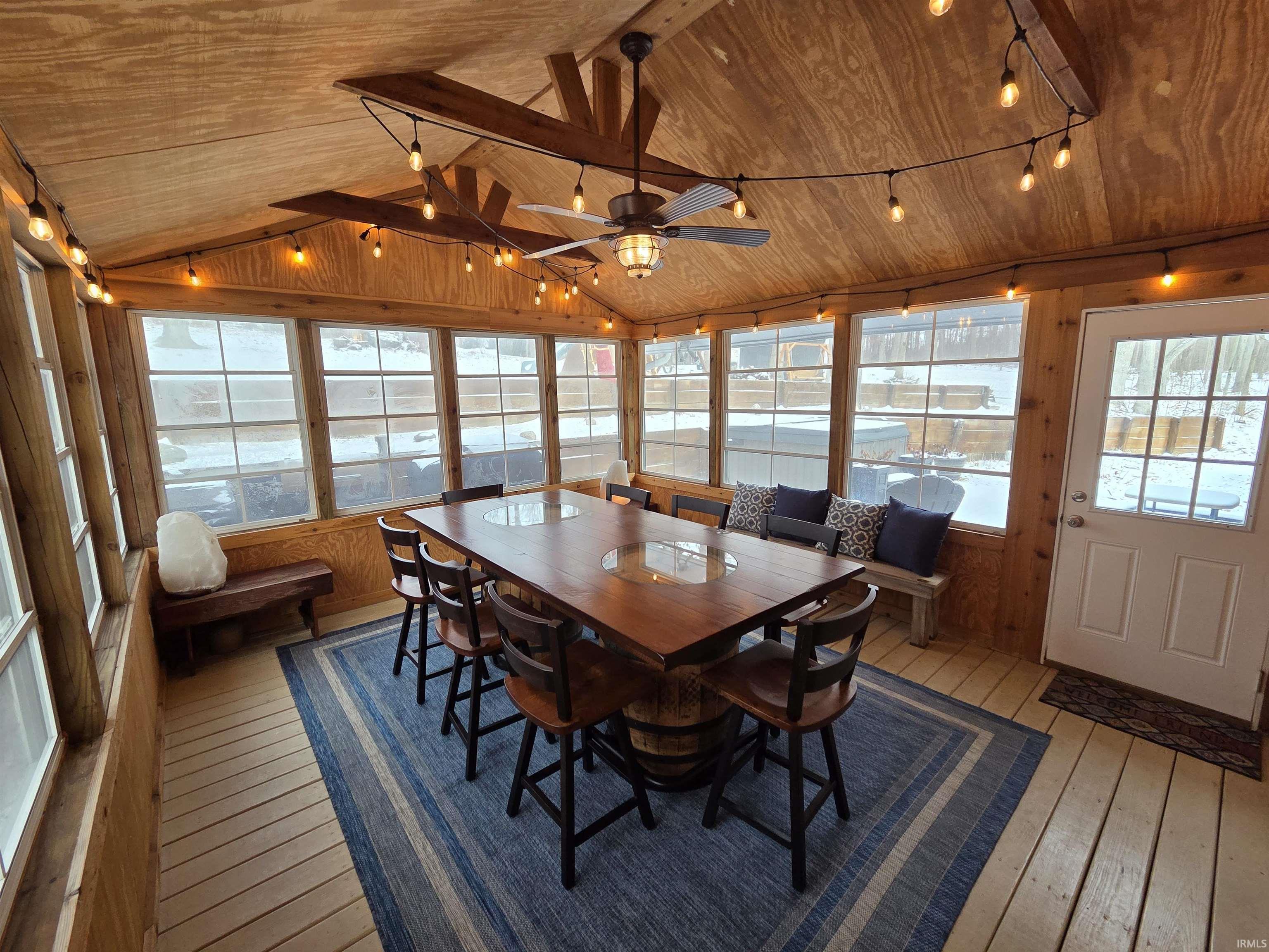 Sunroom / solarium with wooden walls, wooden ceiling, hardwood / wood-style floors, and healthy amount of natural light
