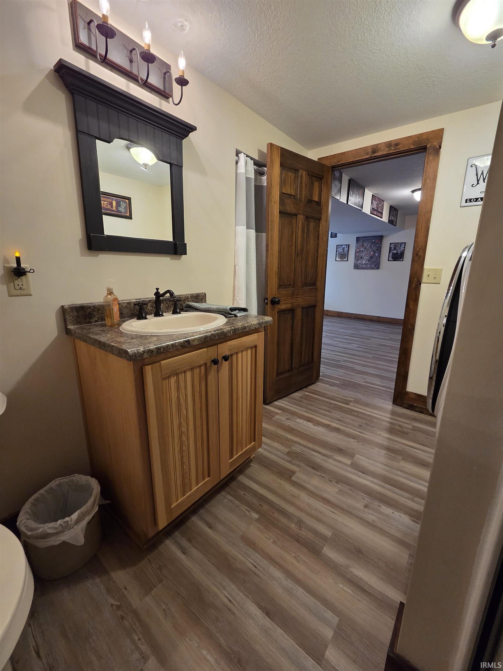 Bathroom with vanity, dark wood-style floors, a textured ceiling, and a shower with curtain