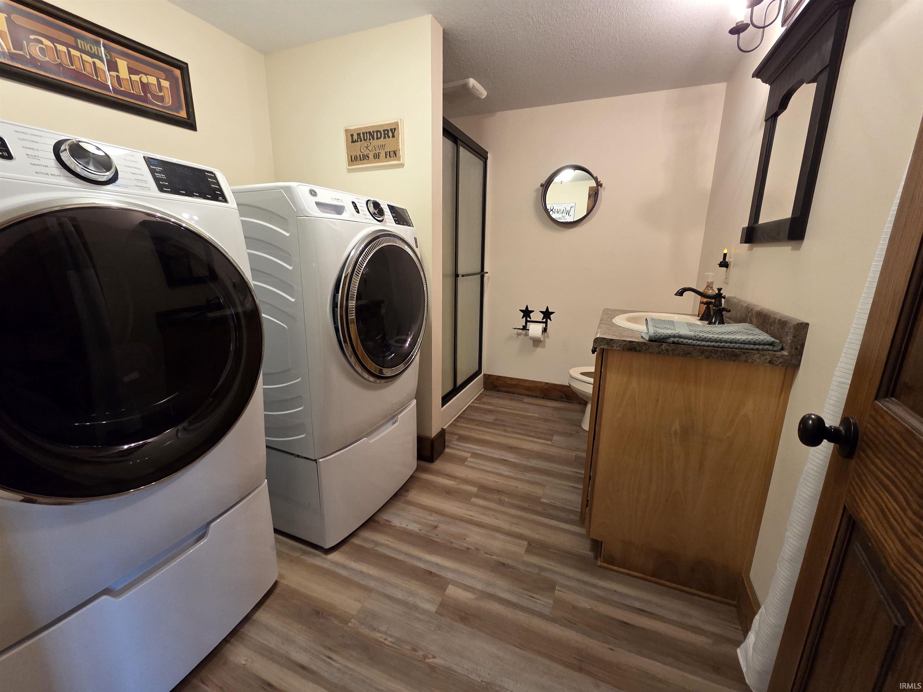 Laundry room featuring washing machine and clothes dryer, dark wood-type flooring, and a textured ceiling