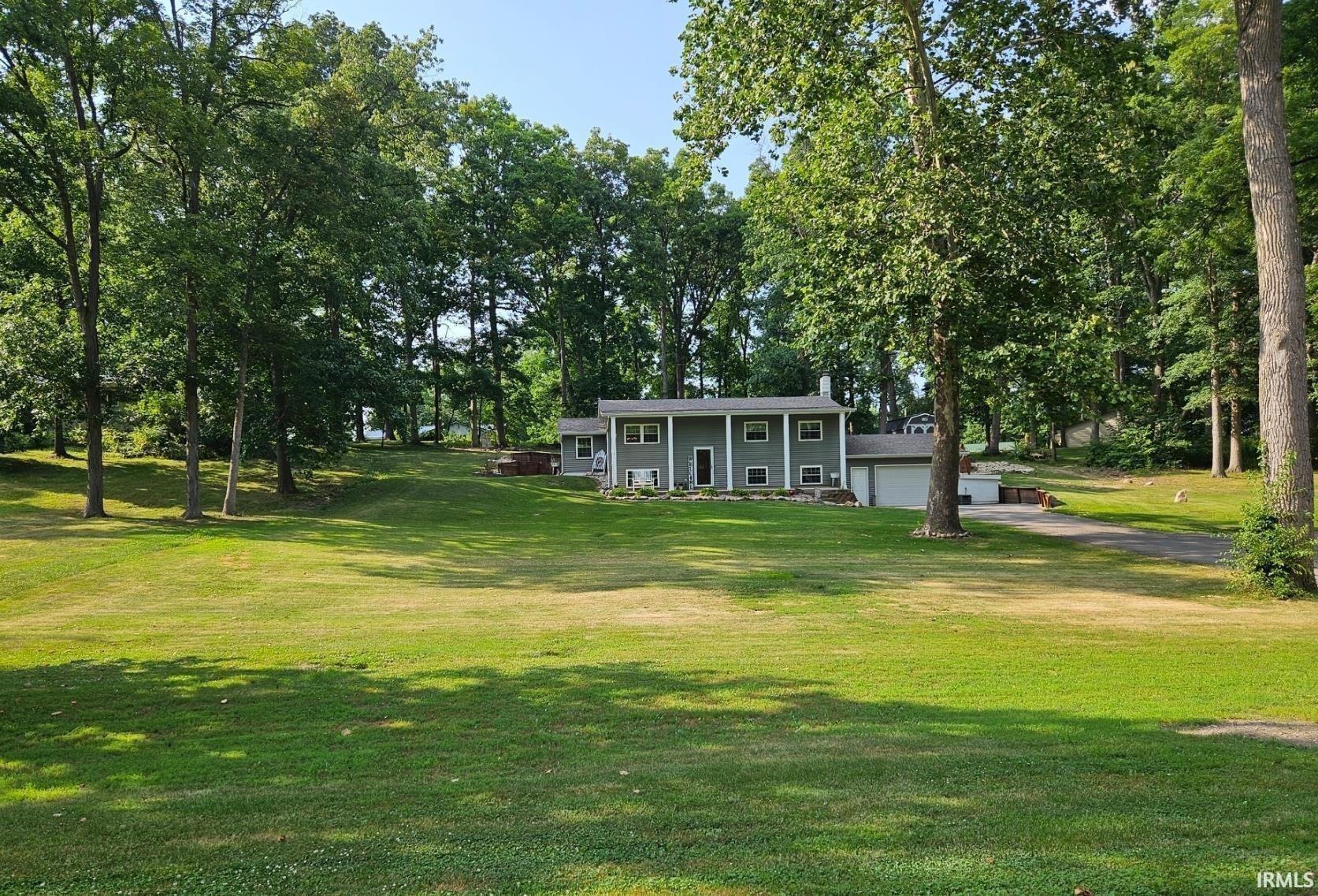 View of property's community featuring a porch, view of wooded area, driveway, and an attached garage