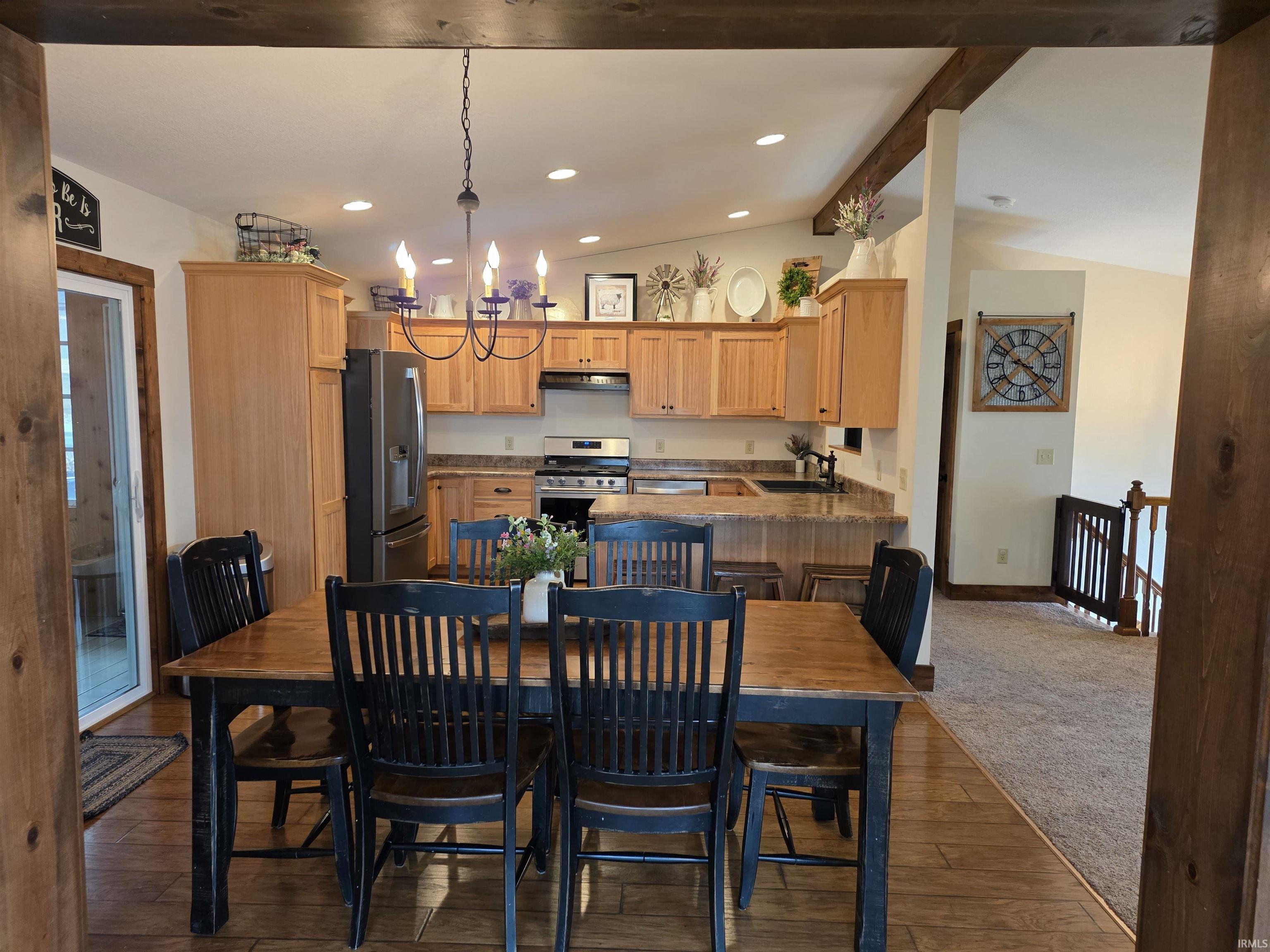Dining space featuring lofted ceiling with beams, dark wood-type flooring, and hanging lights