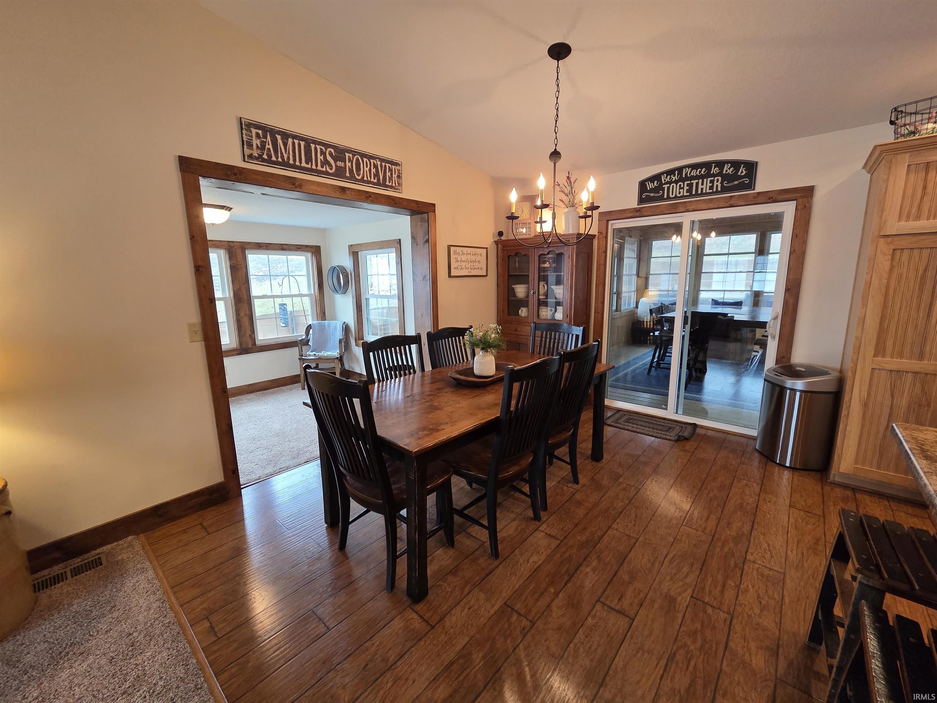 Dining area with a chandelier, dark wood-style floors, and lofted ceiling