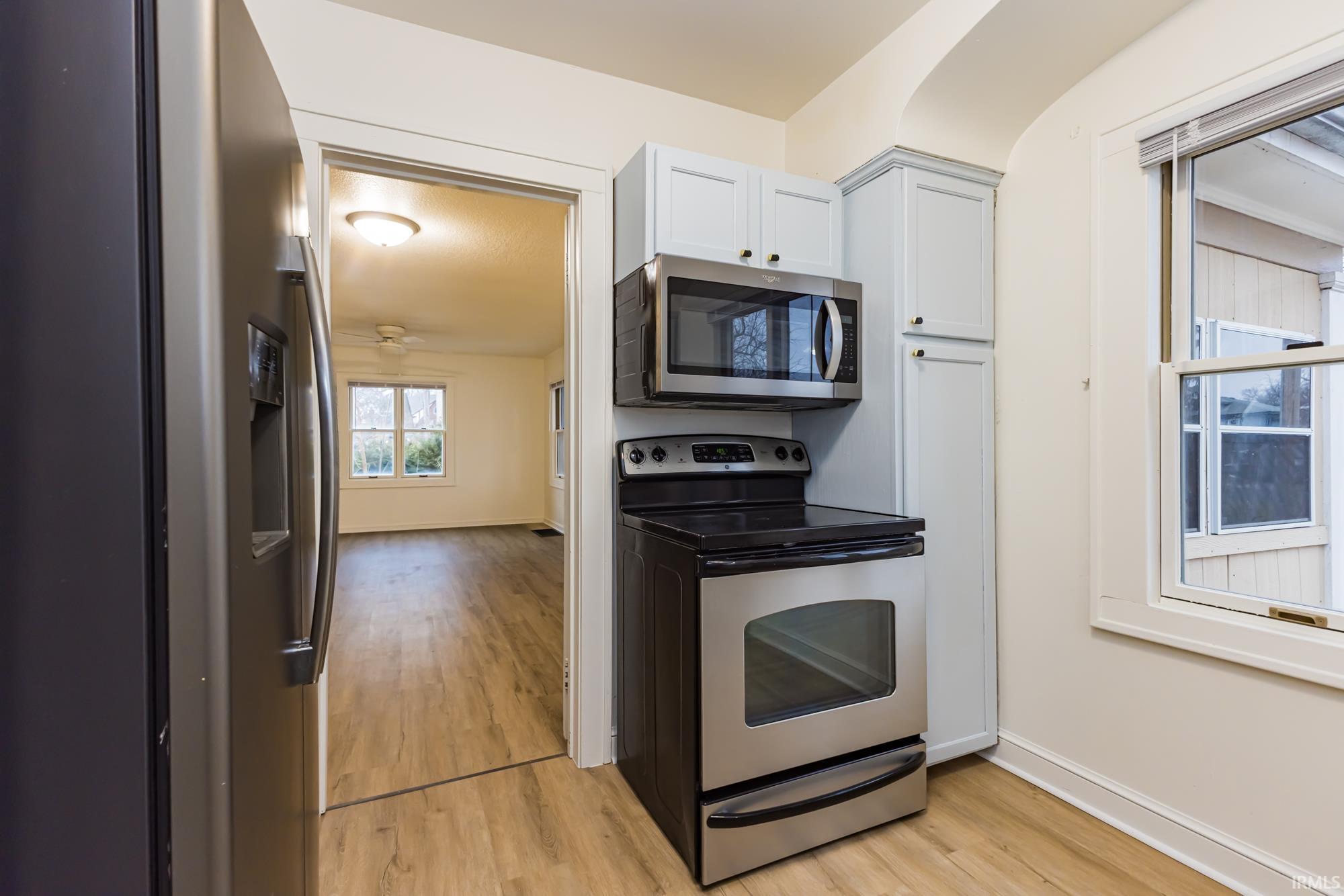 Kitchen with stainless steel appliances, light wood finished floors, and white cabinetry