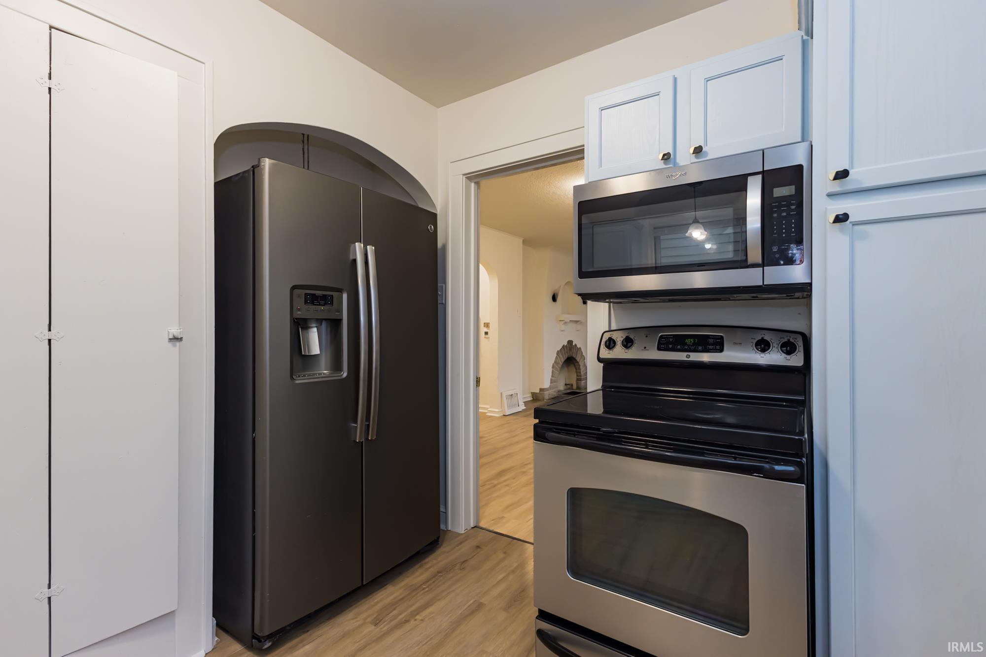 Kitchen with stainless steel appliances, light wood-style flooring, and white cabinetry