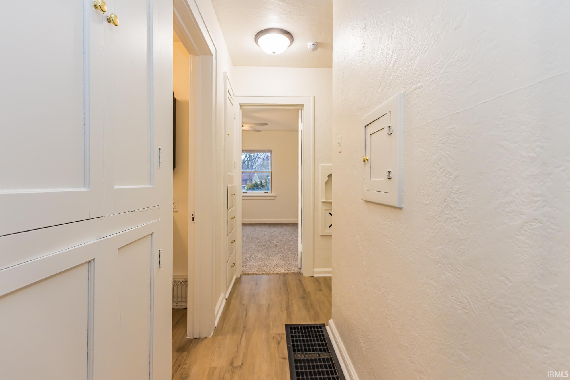 Corridor with a textured wall and light wood finished floors