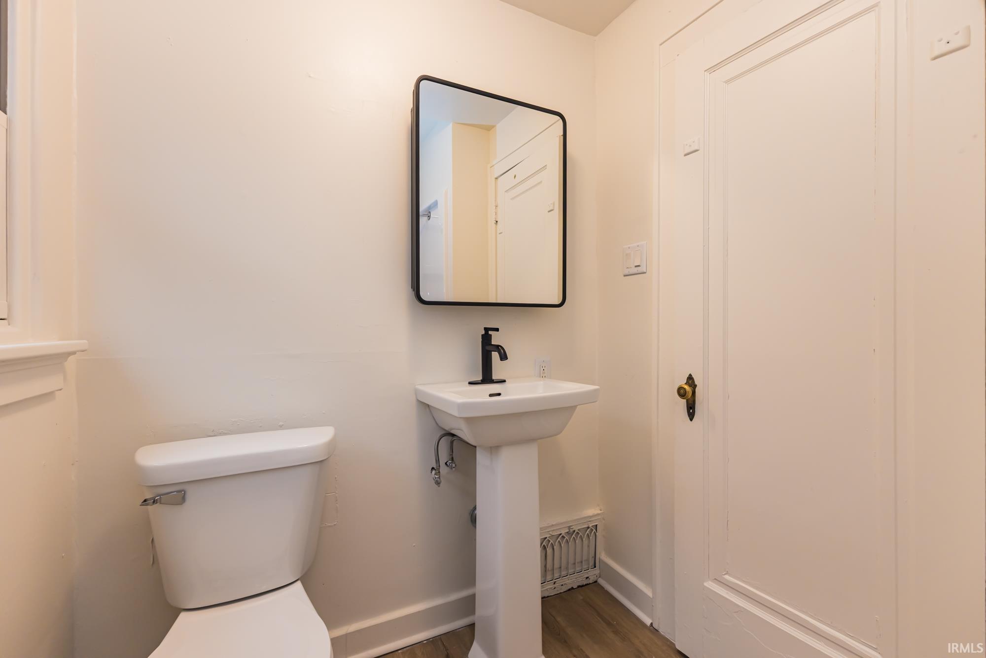 Half bathroom featuring toilet and dark wood-style flooring
