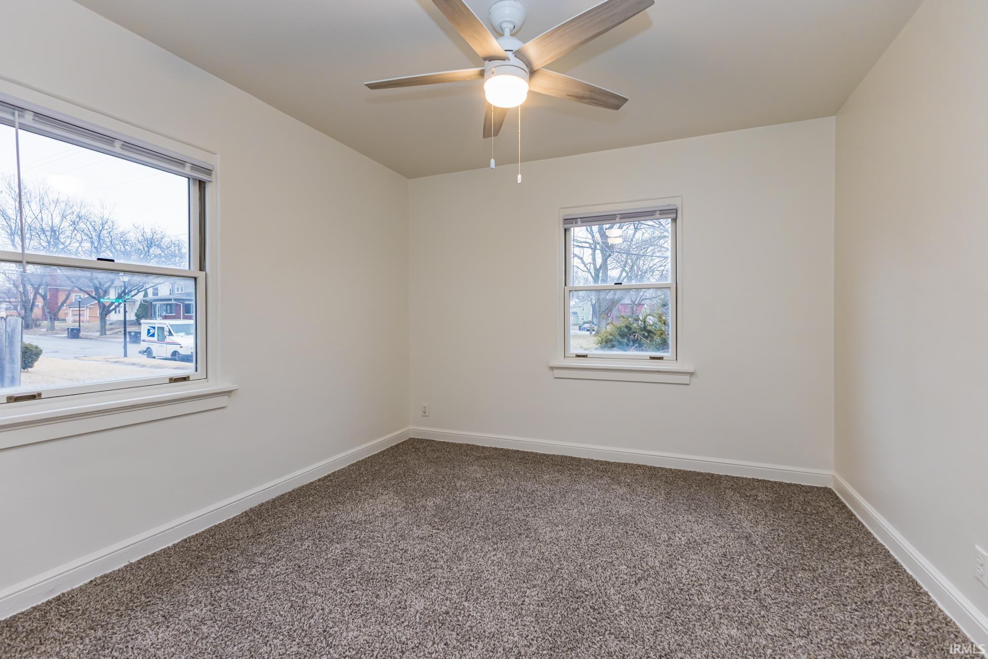 Carpeted empty room featuring baseboards and a ceiling fan