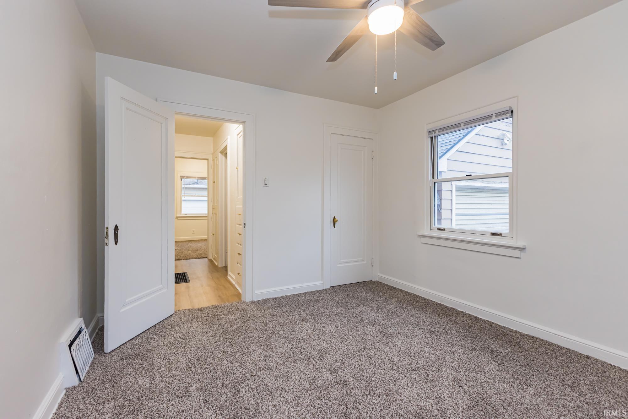 Unfurnished bedroom with light colored carpet and ceiling fan