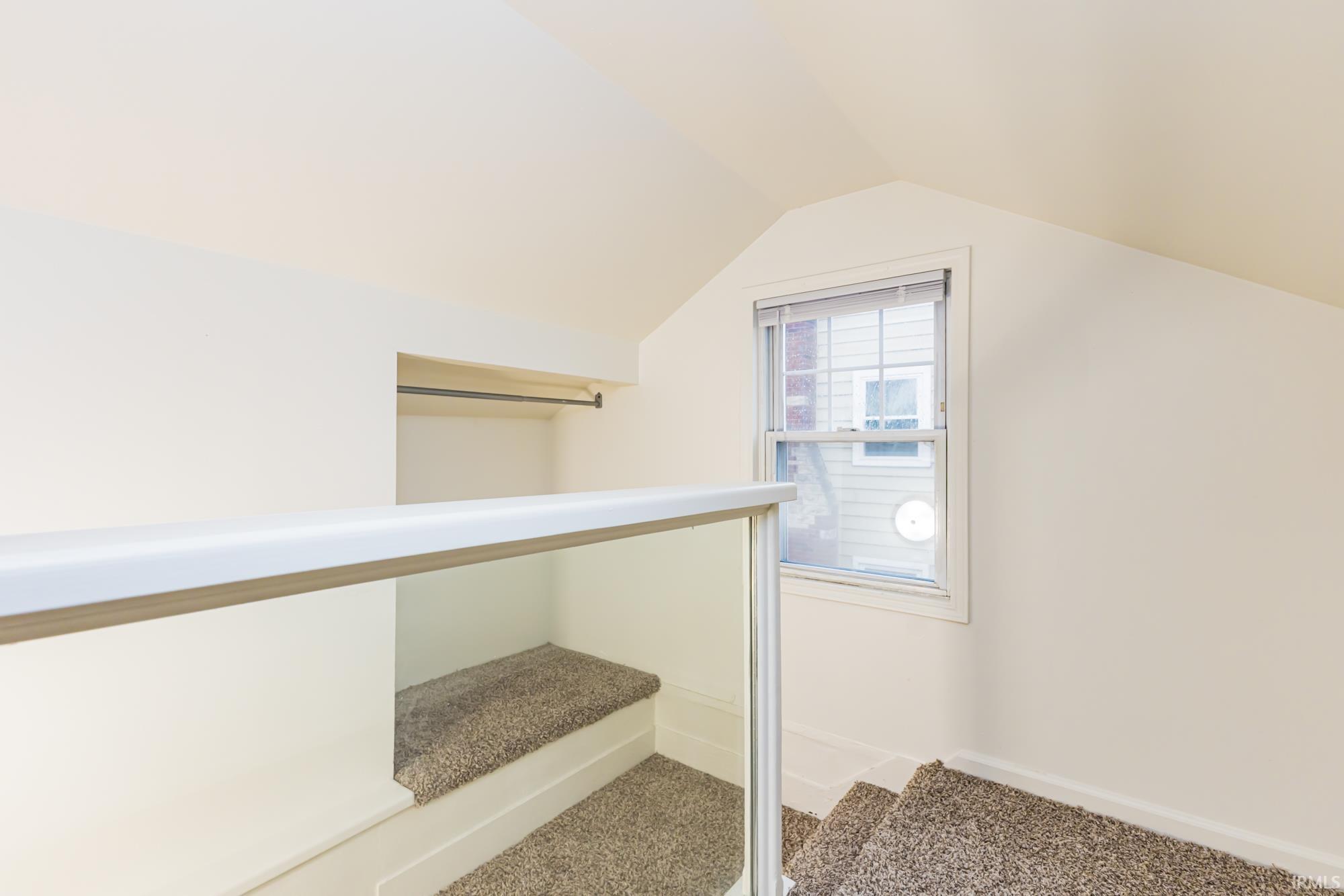 Bonus room with light colored carpet and baseboards