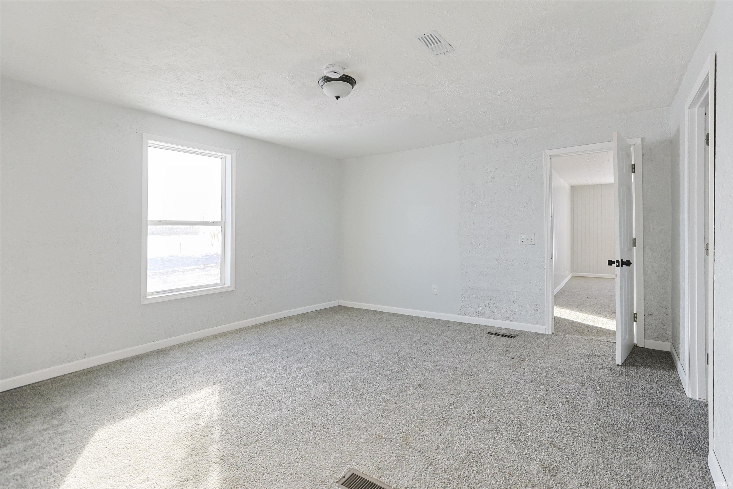 Unfurnished room with light carpet and a textured ceiling