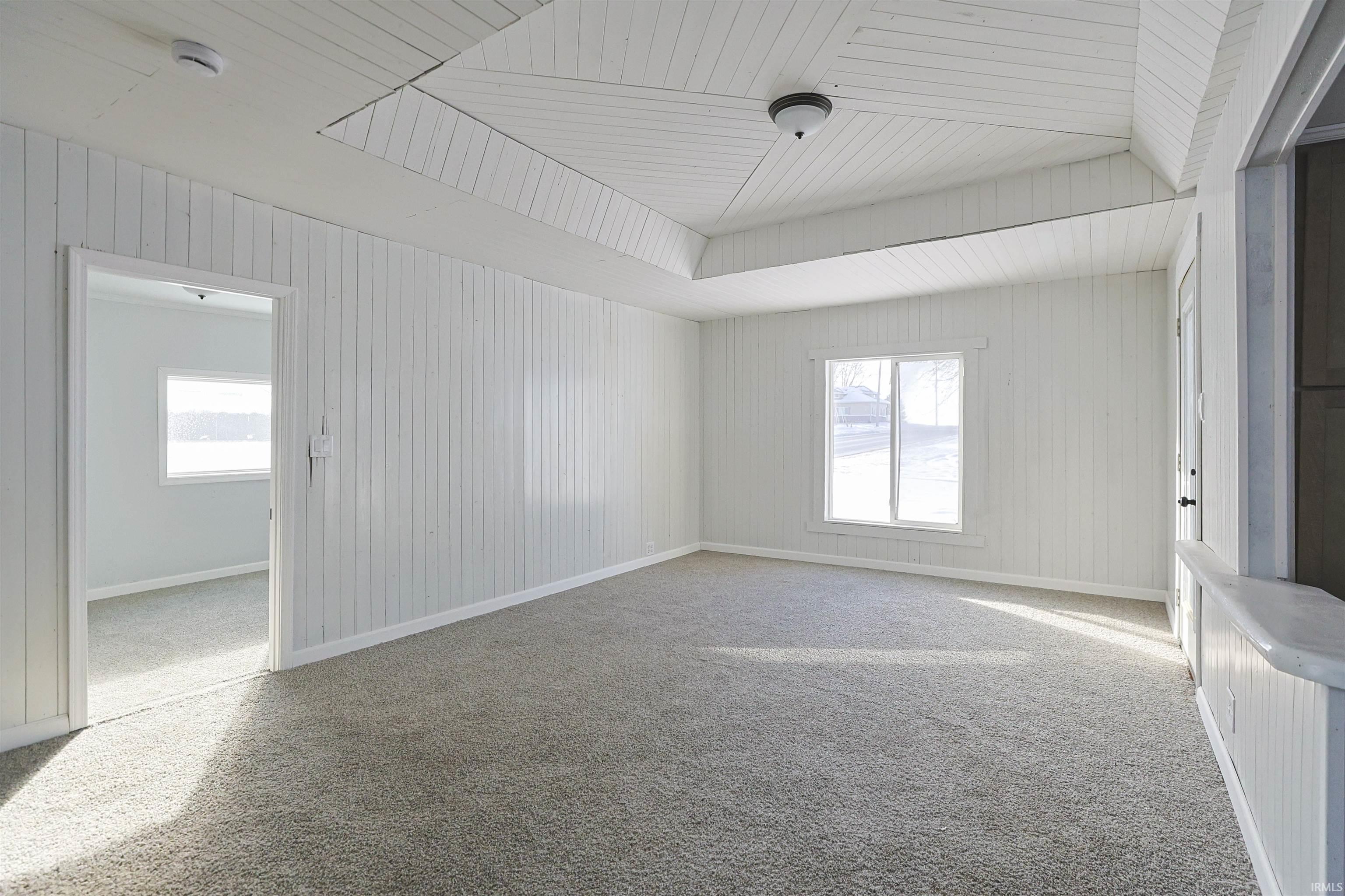Unfurnished room featuring carpet flooring, wood ceiling, and wooden walls